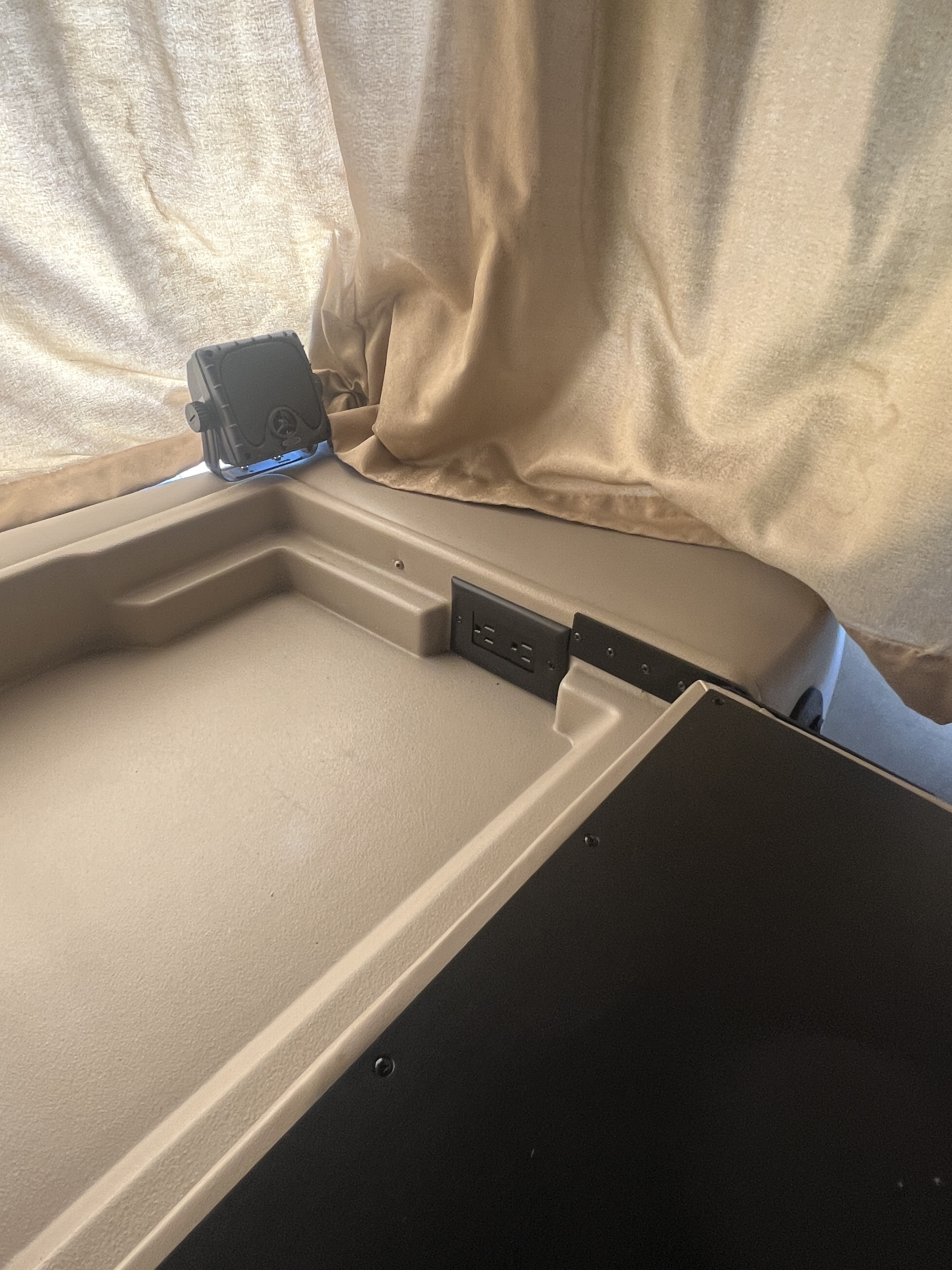 Inside an RV rental: beige interior with power outlets and a mounted light/speaker for comfort.. Thor A.C.E. 2013