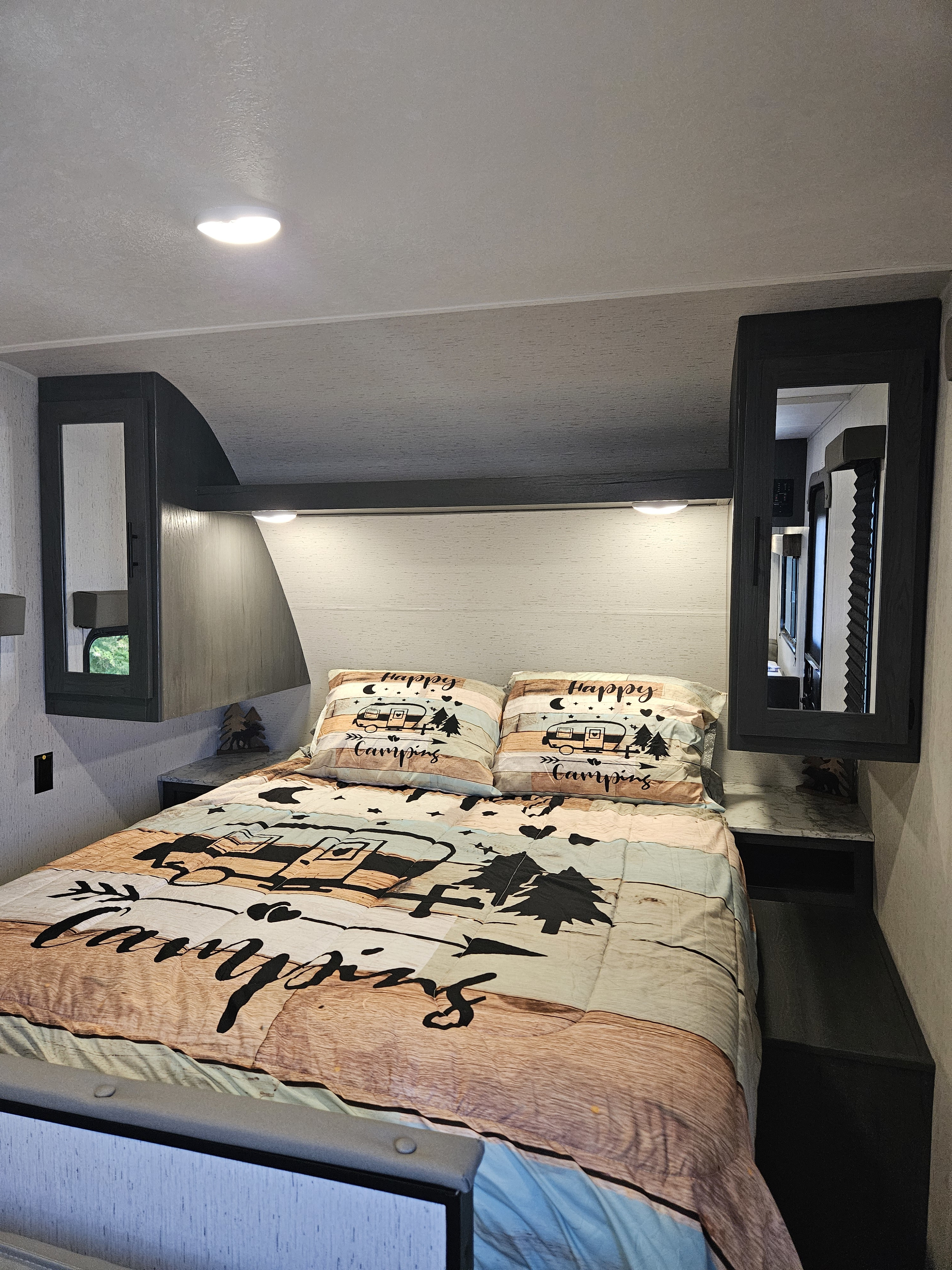 Cozy RV bedroom, perfect for your next rv rental. Features a camping-themed bed, built-in storage, and soft lighting.. Dutchmen TT 2024
