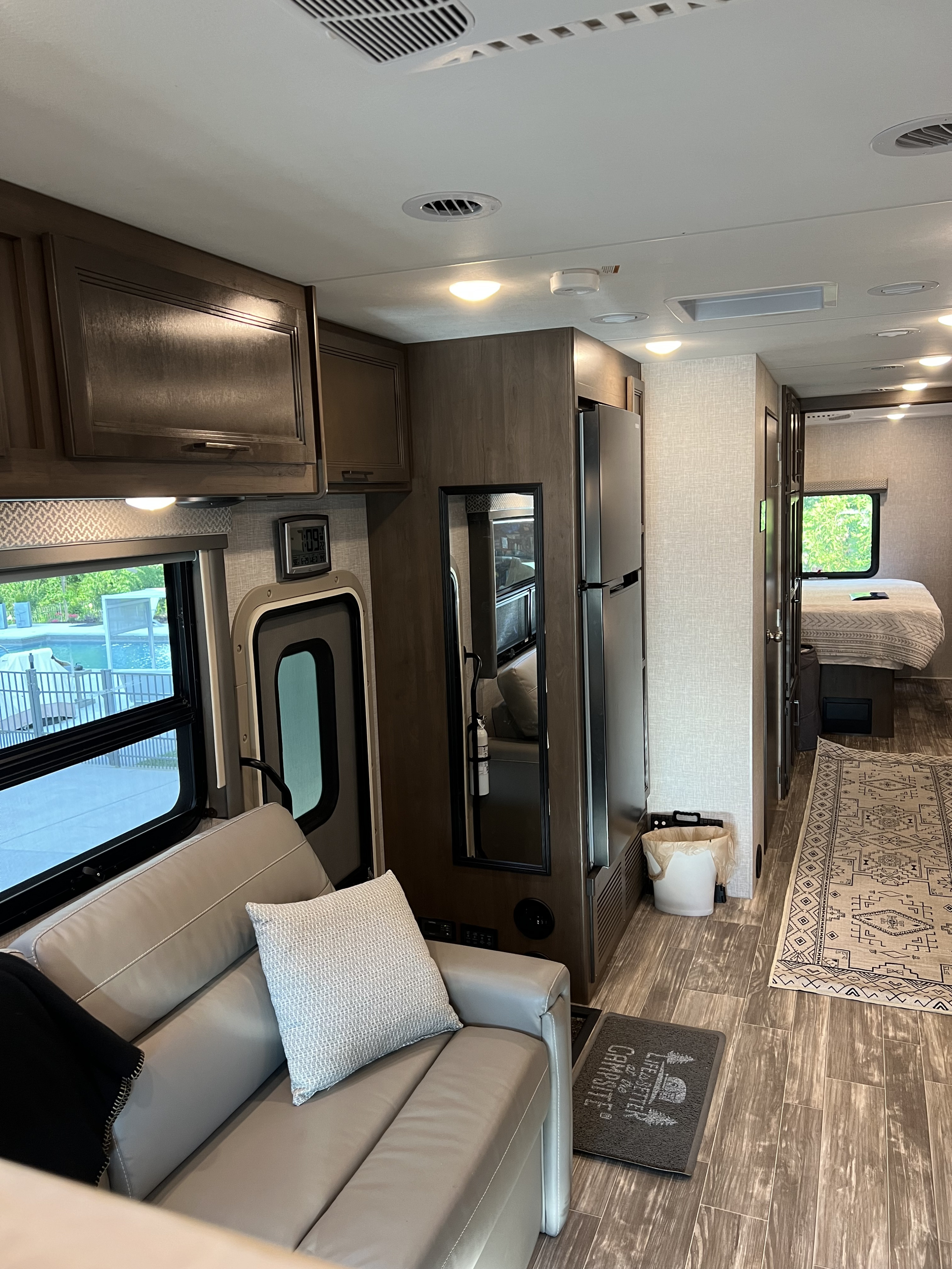 Comfortable RV rental interior showcasing a living area with a plush couch, full kitchen, and a cozy bedroom.. Thor Hurricane 2022
