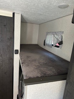 Cozy RV rental bunk bed for comfortable travel, with a window and privacy curtains.. Sportsmen 181BH 2022