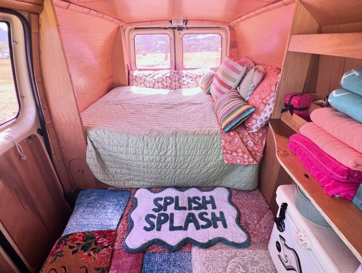Explore this charming rv rental's interior: a comfy bed, pink walls, colorful towels, and a fun "Splish Splash" mat.. Ford E250 Eagle Camper 2006