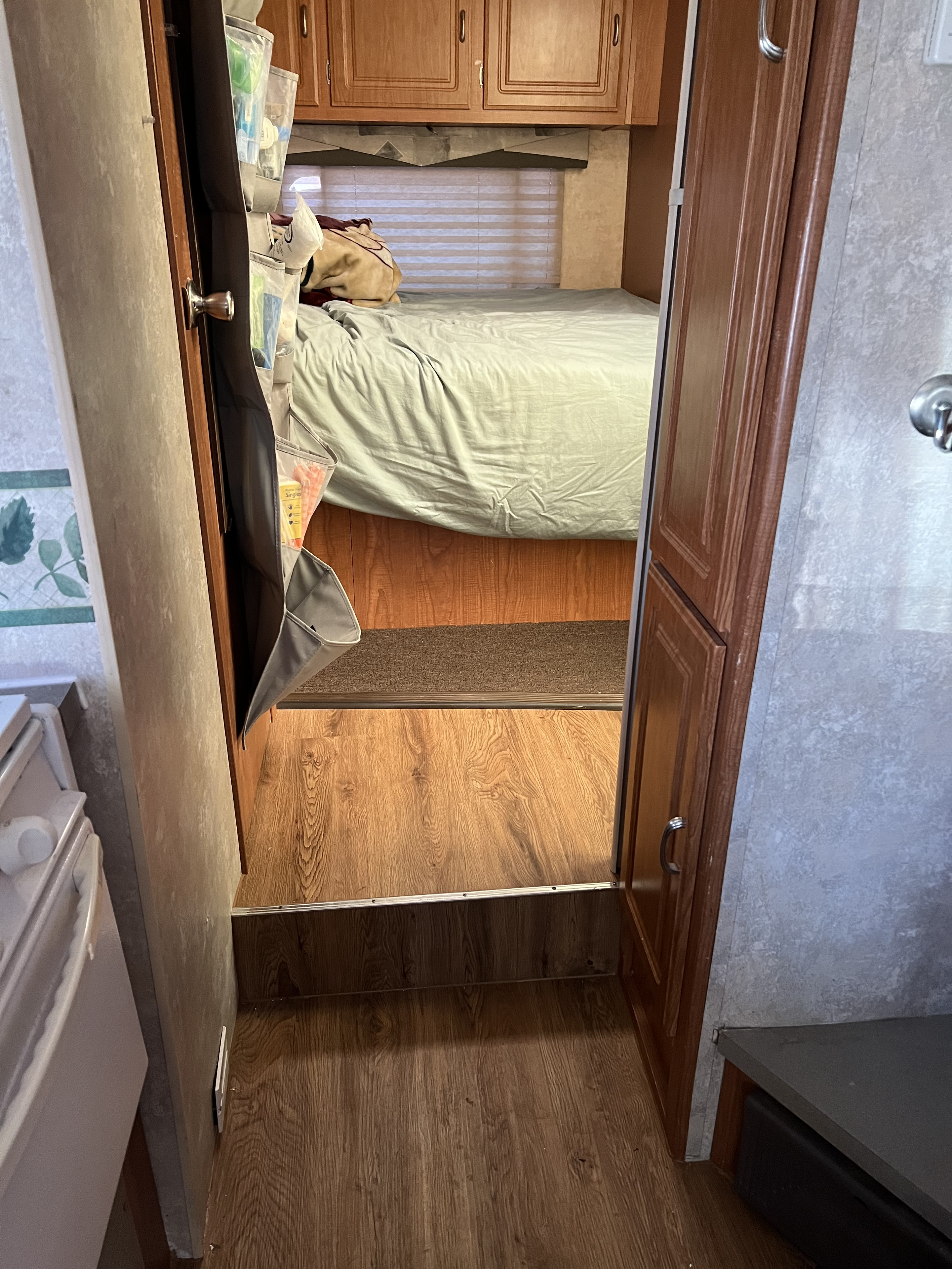 View from the living area into the cozy bedroom of an RV rental, featuring a bed and clever over-door storage.. Coachmen Freelander 2007