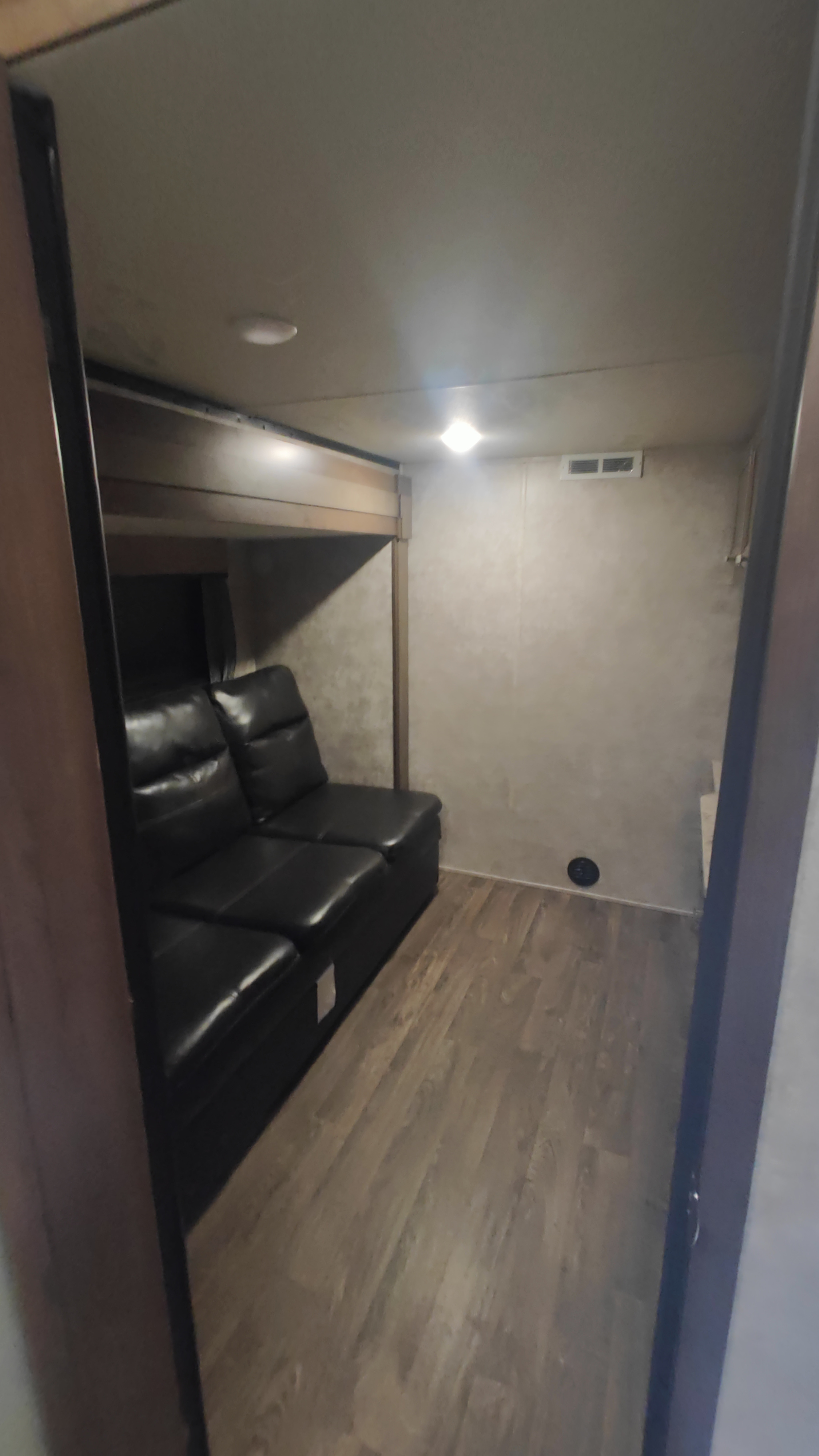 Spacious RV rental bunkhouse with a comfy black sofa, wood flooring, and bright lighting for a relaxing trip.. Highland Ridge RV Open Range 2019