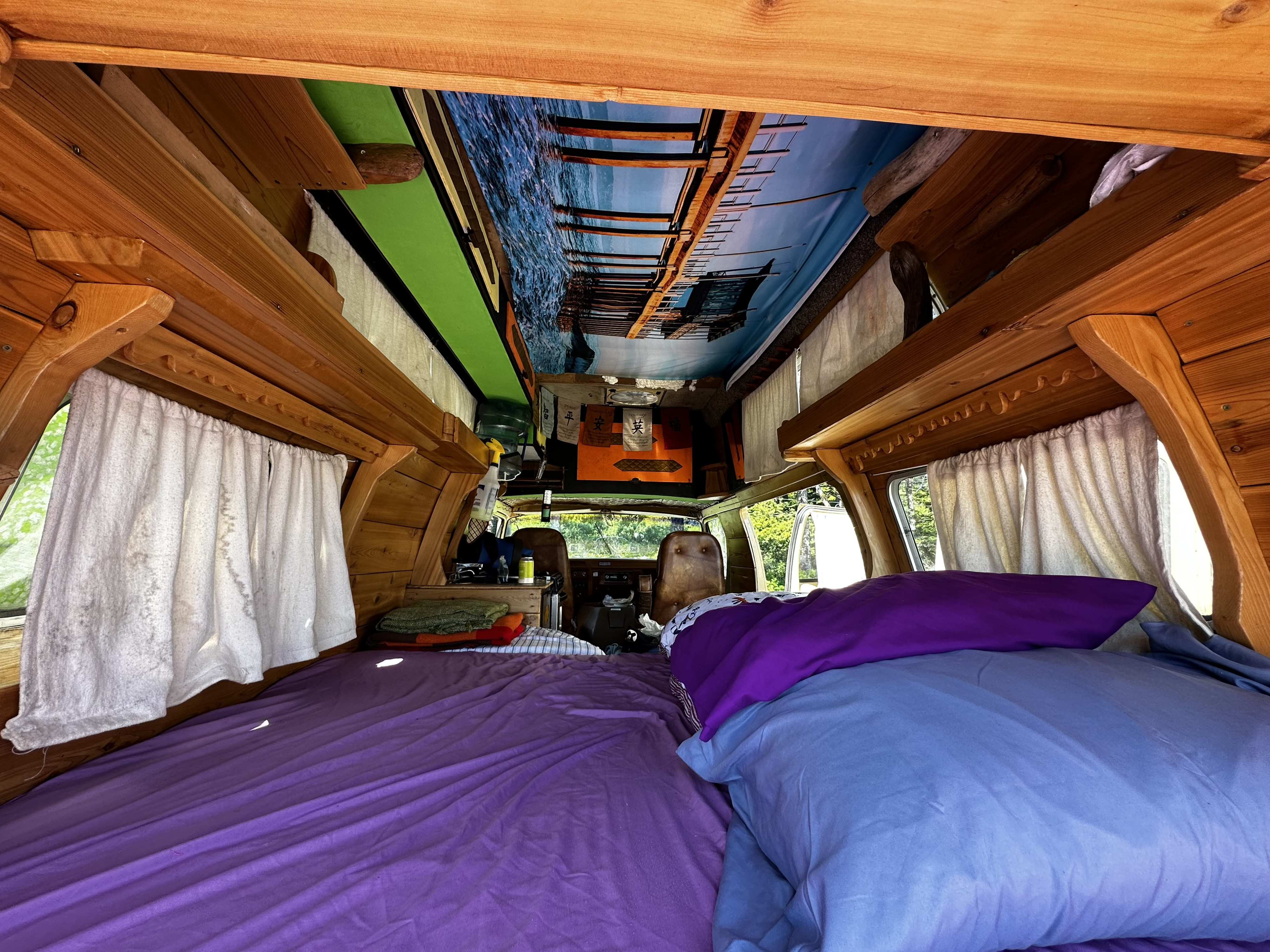 RV rental: inviting interior with a bed, rich wood finishes, and a serene pier ceiling mural.. Dodge B Van 1977