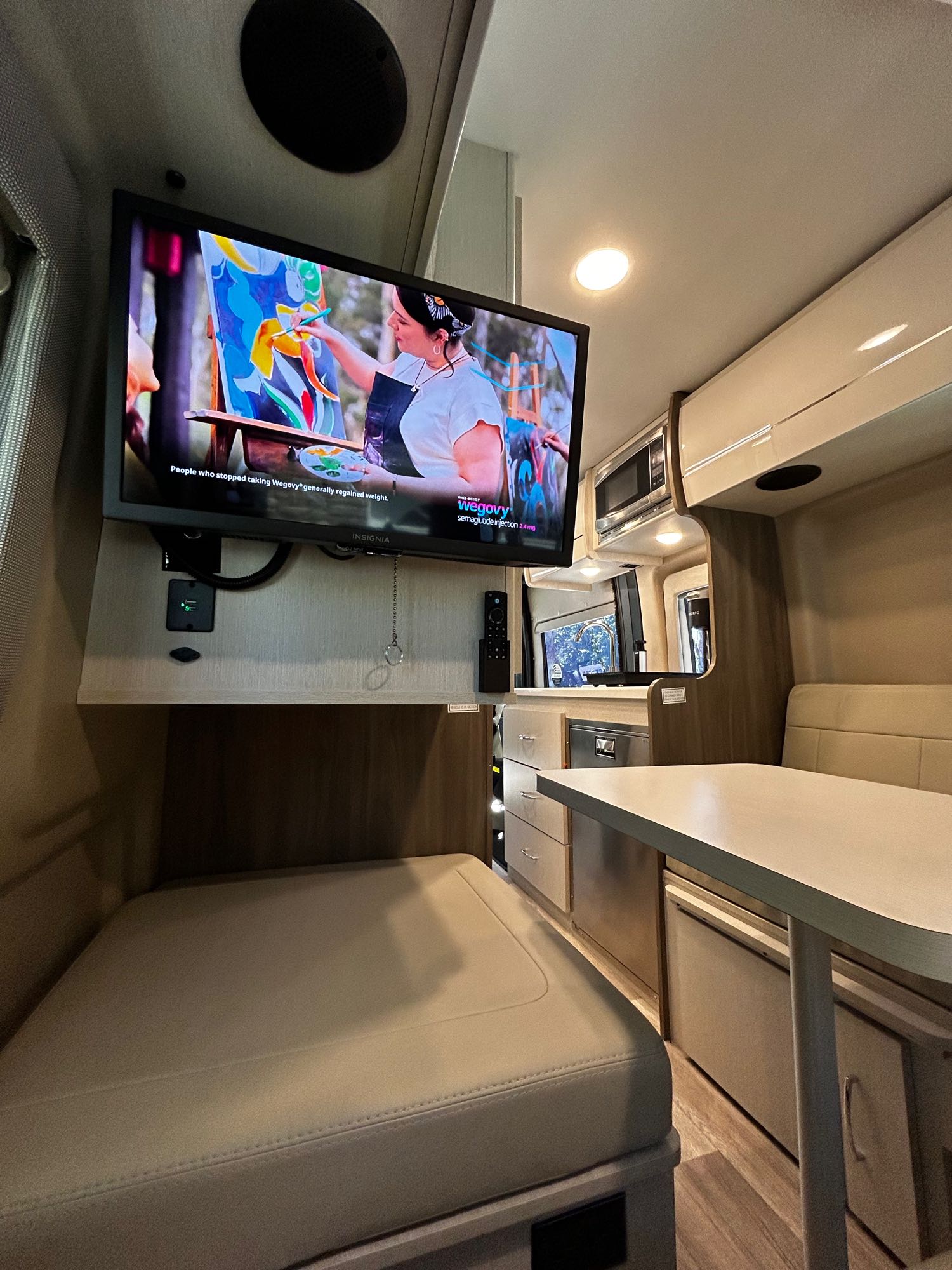 RV rental's functional interior: mounted TV, compact kitchen, dining area, & bed for comfortable travel.. Thor Tellaro 2024
