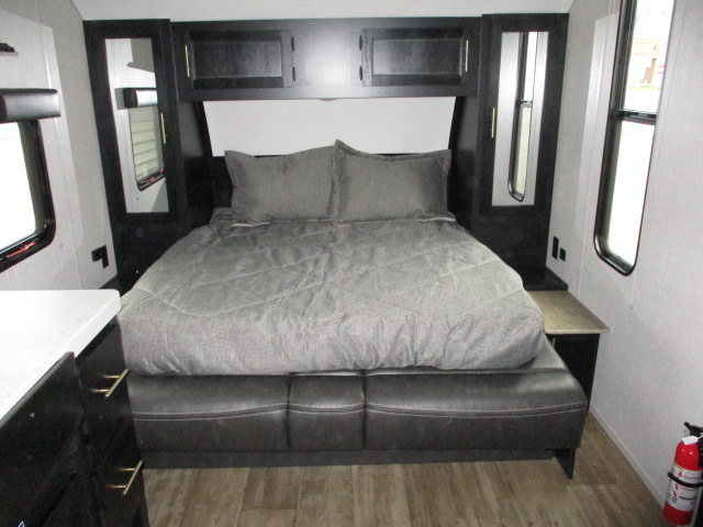 RV rental bedroom showcasing a compact, modern interior with a convertible bed, overhead storage, and windows.. Forest River Cherokee Grey Wolf 2022
