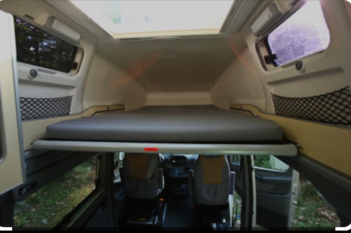 Compact RV rental interior featuring an elevated bed, perfect for a comfortable night's sleep in nature.. Mercedes-Benz Sprinter 2005