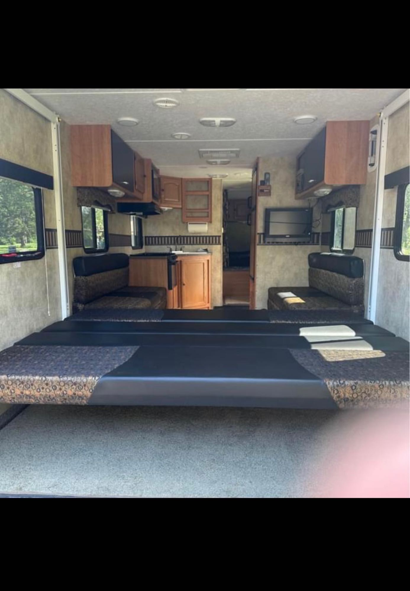 Explore this cozy RV rental interior featuring convertible beds, a compact kitchen, and a TV for your travels.. Keystone Passport 2009