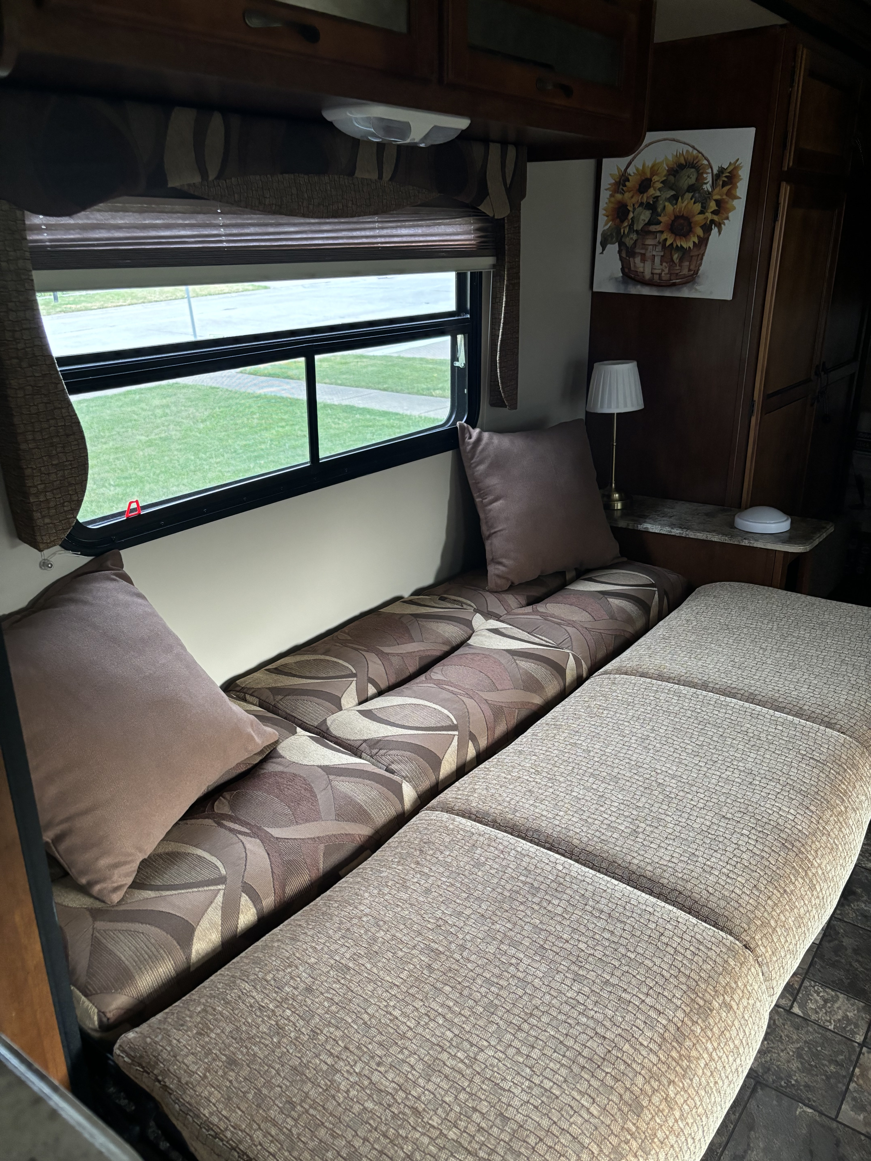 Comfortable RV rental interior with patterned and textured cushions, a sunny window, and overhead storage.. Coachmen Catalina Deluxe Edition 2013