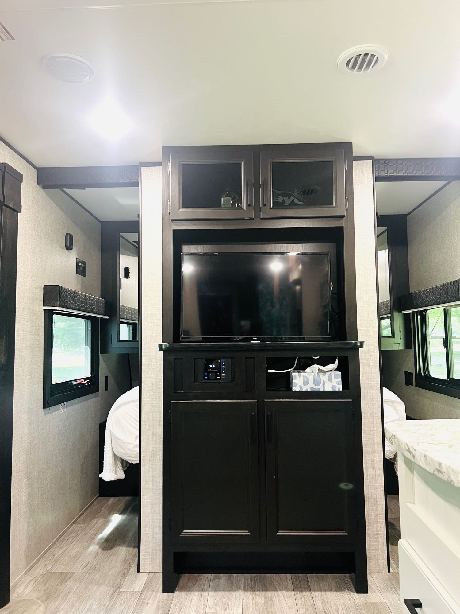 Modern RV rental interior with a central TV unit, overhead cabinets, and twin bed areas. Designed for compact comfort.. Jayco Jay Flight SLX 2022