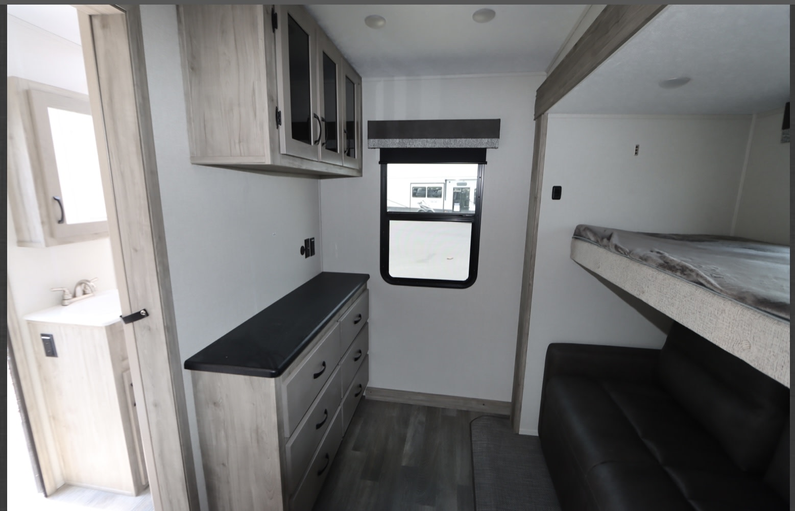 RV rental: Compact interior with bunk beds, sofa, dresser, and partial view of bathroom. Maximized living space.. Coachmen Chaparral 2024
