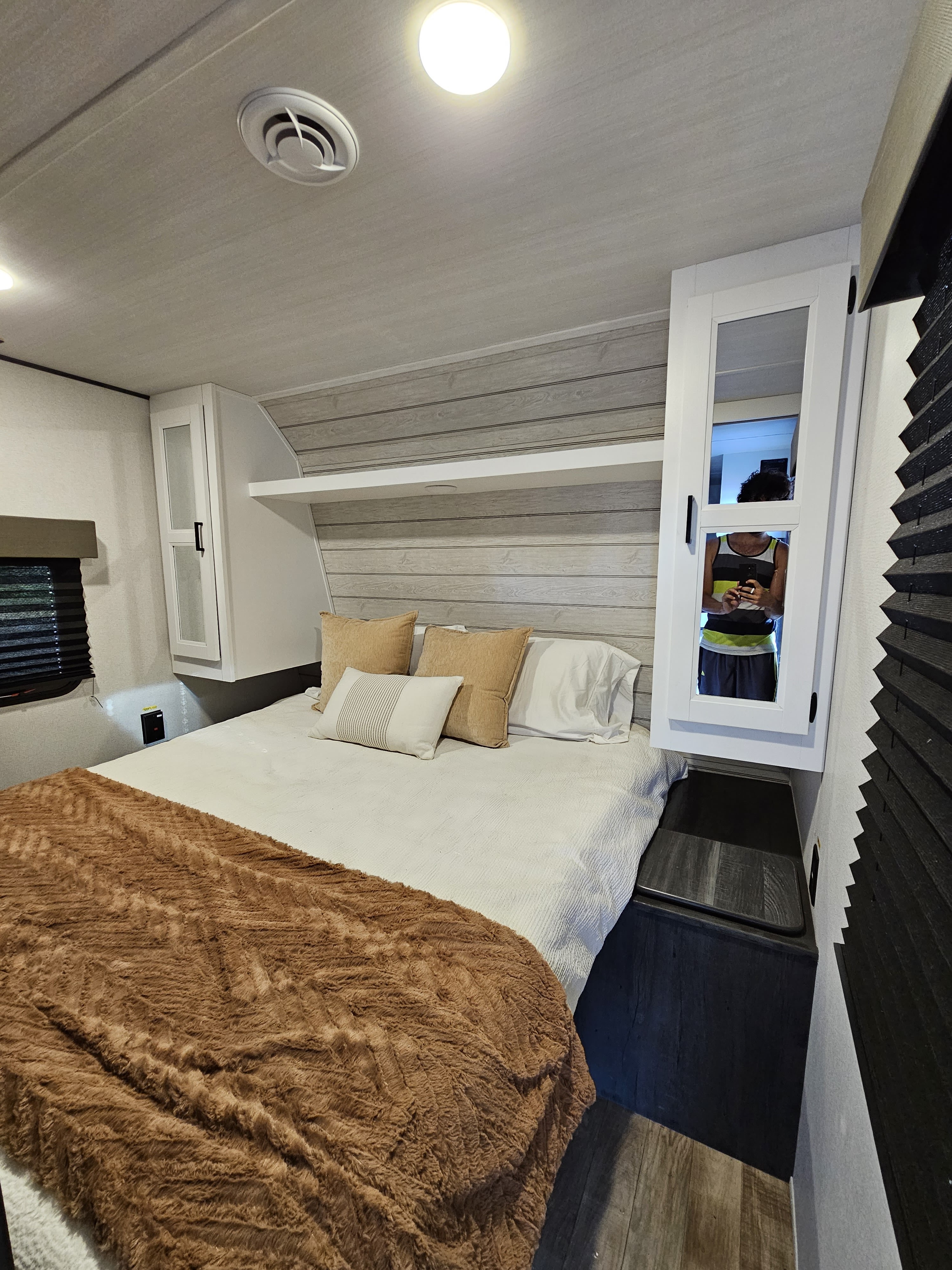 Cozy RV rental bedroom with modern built-in storage, a comfortable bed, and wood-look accents.. Keystone RV Hideout 2023