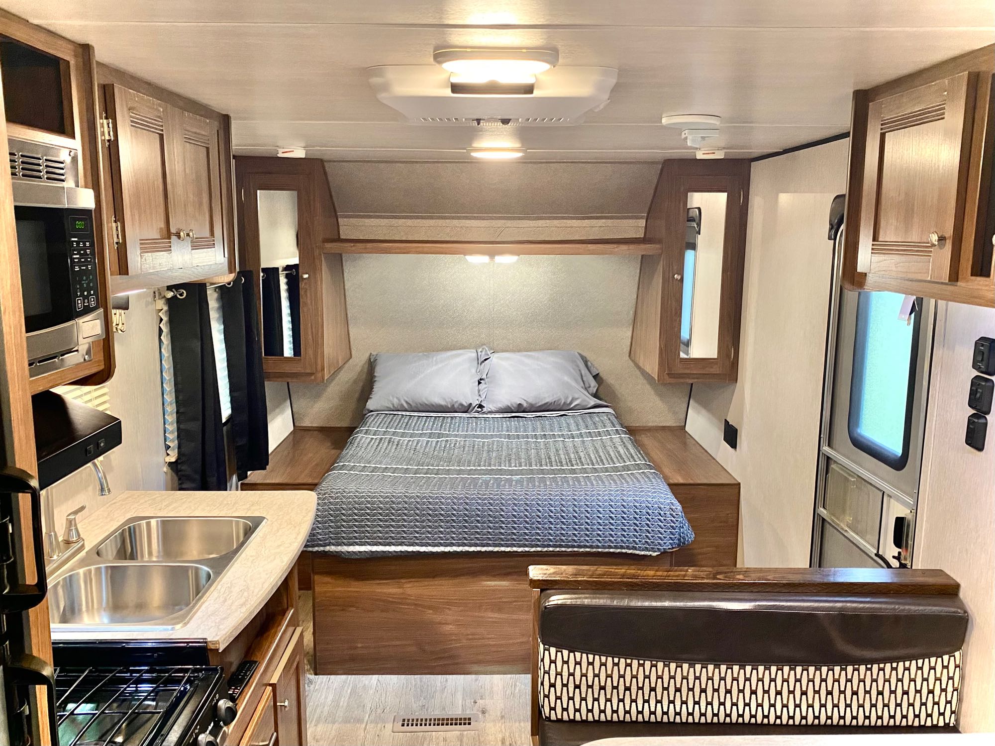 Explore this bright rv rental interior, featuring a cozy bed, compact kitchen with dual sinks, and dinette area for comfort.. Heartland RVs Prowler Lynx 2018