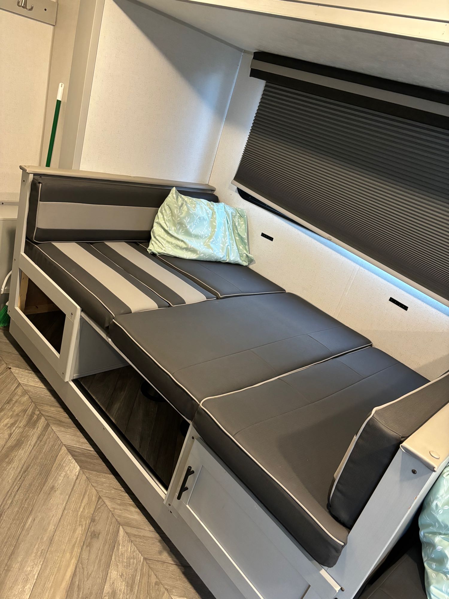 Cozy RV rental interior showcasing a versatile dinette with grey cushions, converting to a bed, with storage and a window blind.. Forest River Salem FSX PLATINUM 2021