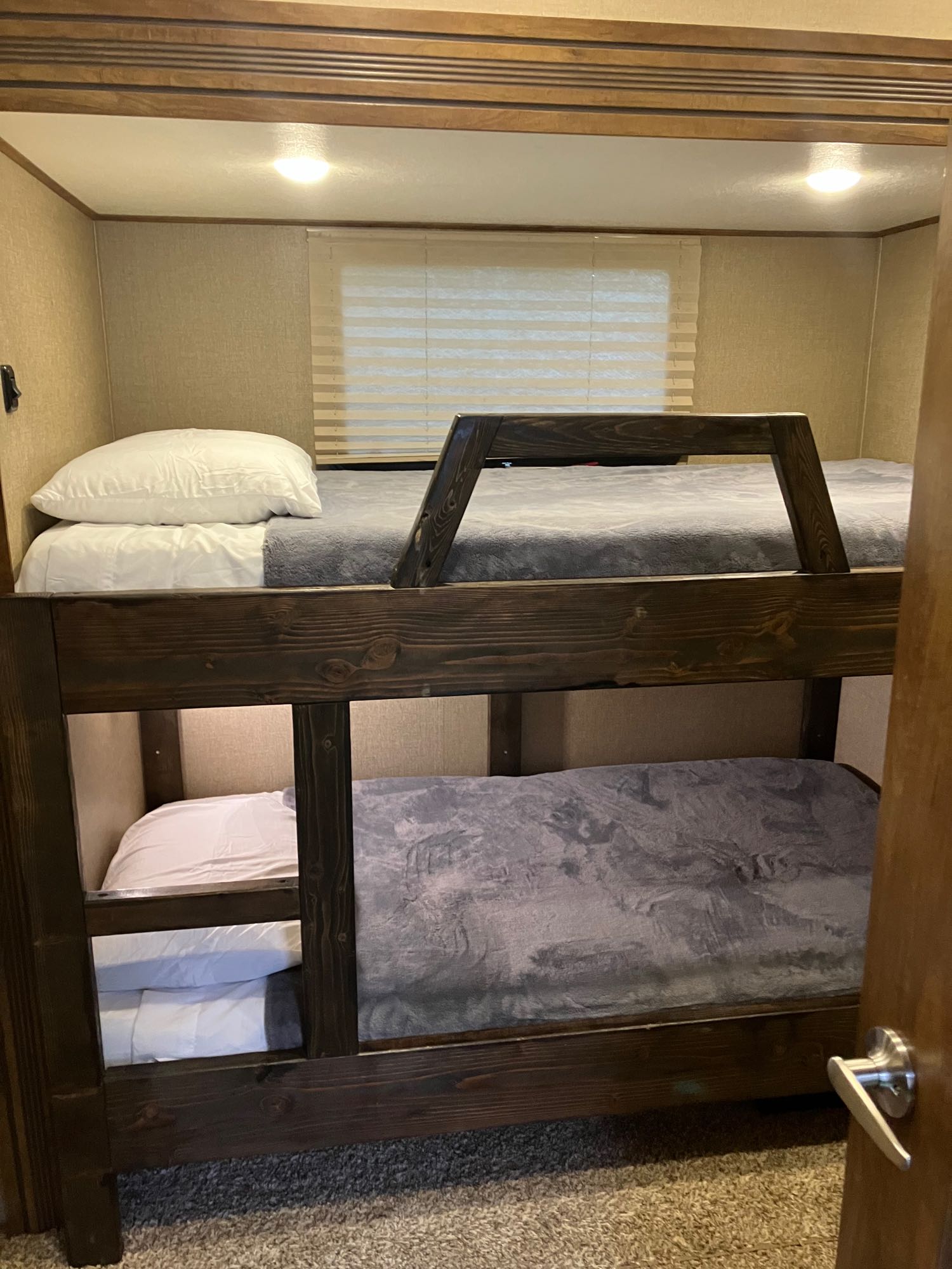 RV rental interior features bunk beds with dark wood frames. White sheets and grey blankets make for a cozy sleeping area.. Forest River Coachmen Chaparral 2017