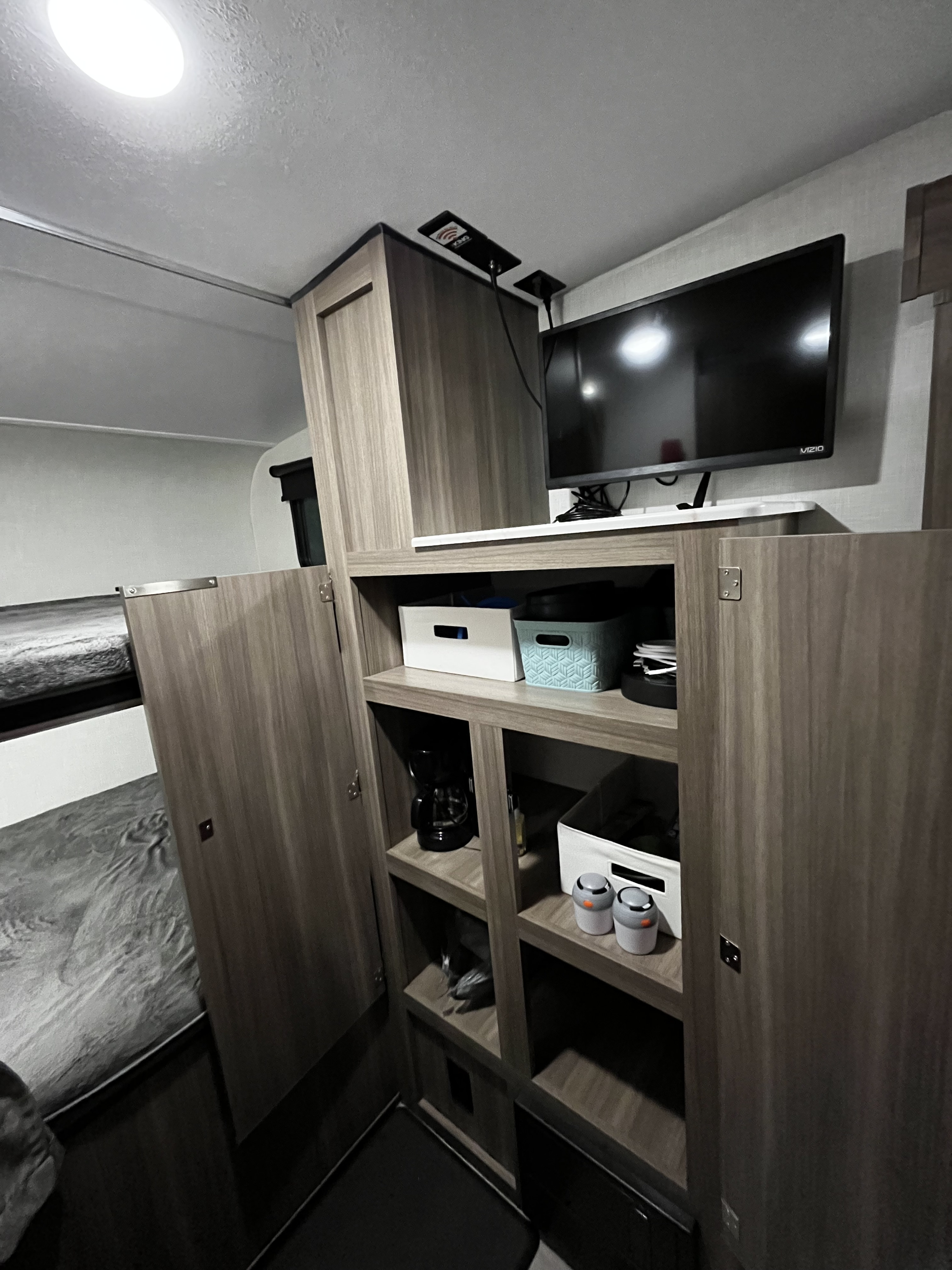 Cozy RV rental interior: bunk beds, full storage with bins and a coffee maker, plus a mounted TV.. Venture SN211VDB 2024