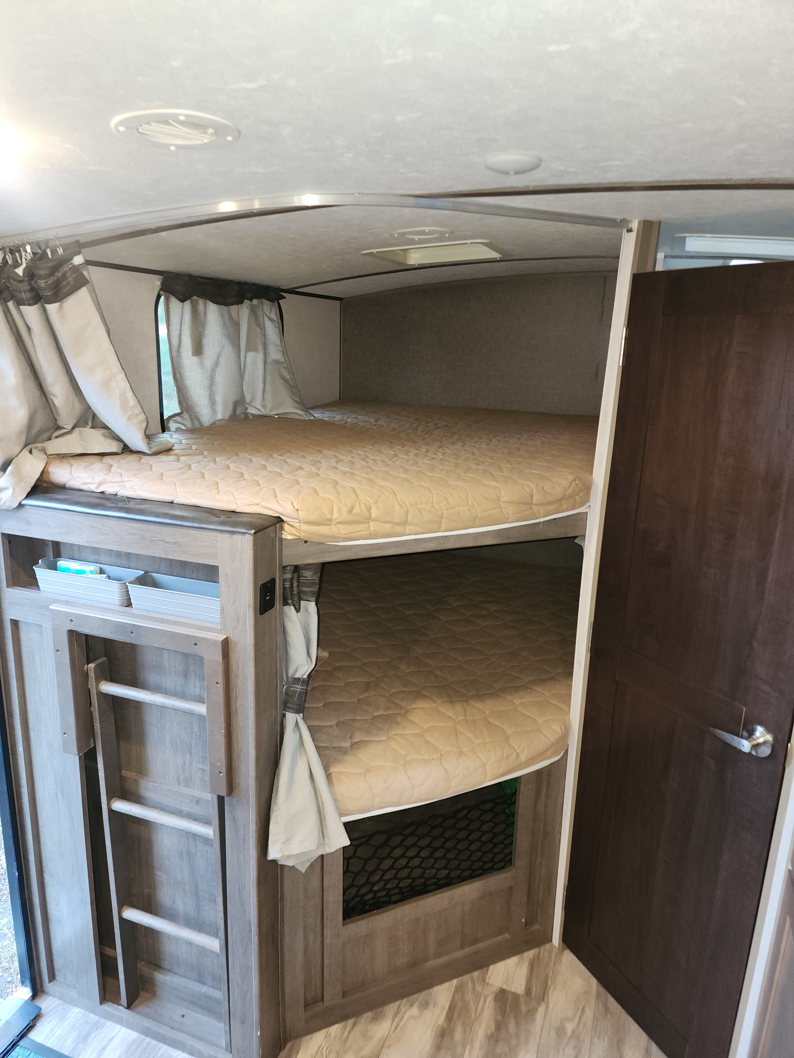 Inside an RV rental: two comfy bunk beds with a ladder & storage cubbies. Ideal for families and visually impaired users.. Forest River Surveyor Legend 2019