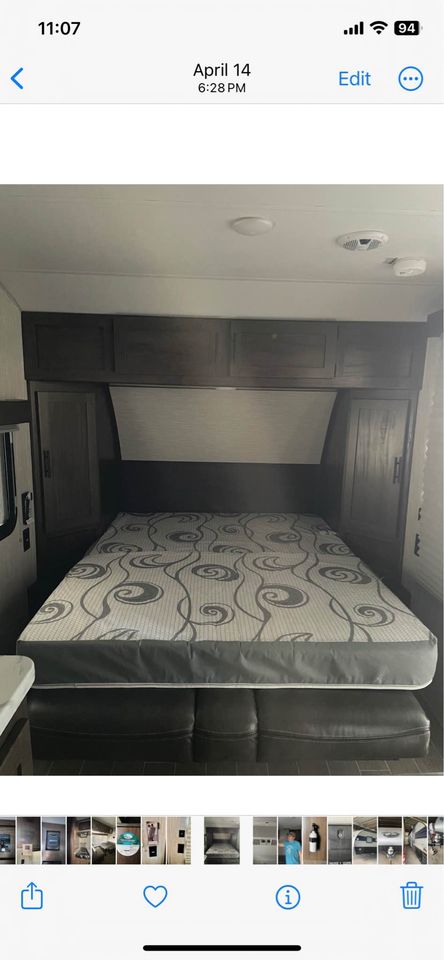 RV rental interior: compact bedroom with a patterned mattress, dark wood cabinets, and leather seating.. Forest River Cherokee Wolf Pup 2020