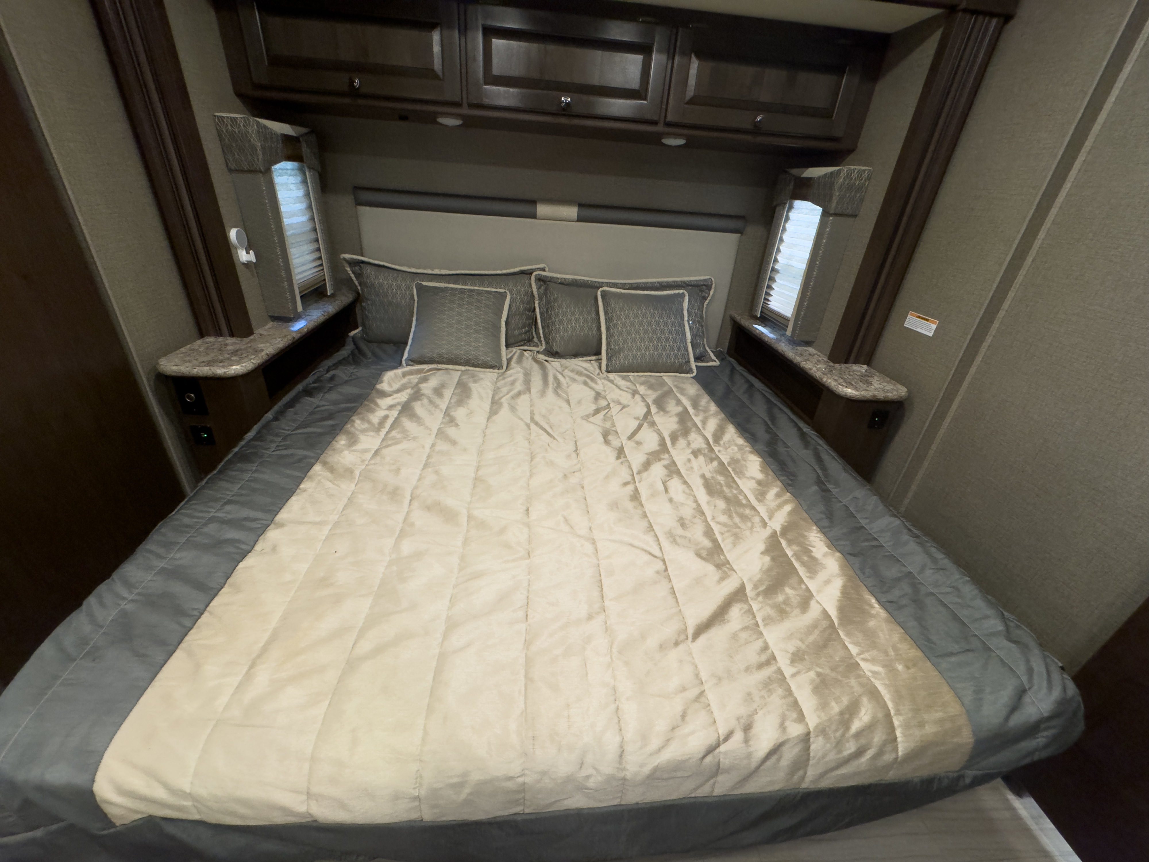 Cozy RV rental bedroom with a queen bed, overhead cabinets, and built-in nightstands for comfortable travel.. Thor Windsport 2020