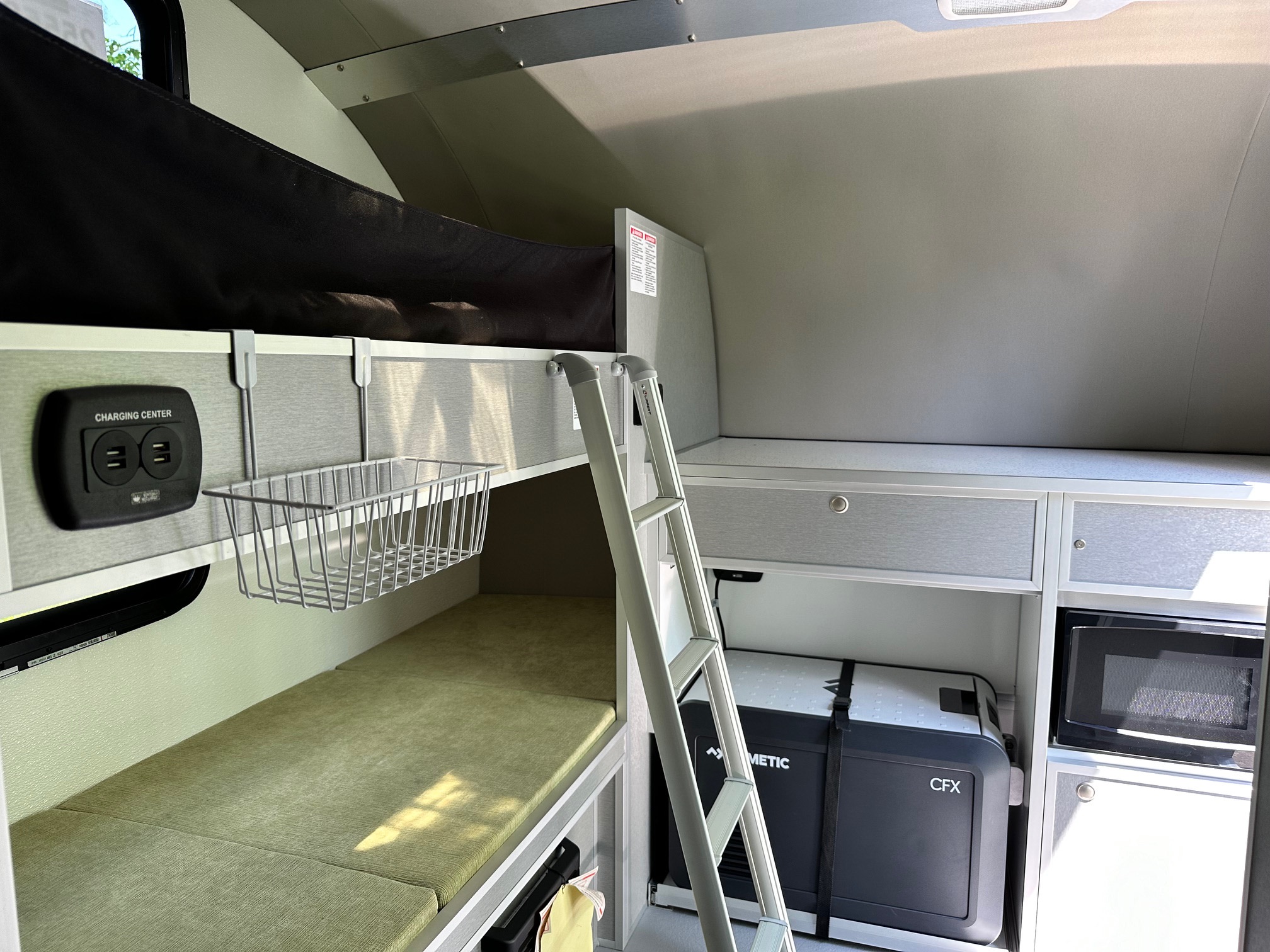 This rv rental interior offers practical bunk beds, a charging center, Dometic fridge, and microwave, ideal for compact travel.. Helio O4 Evo 2023