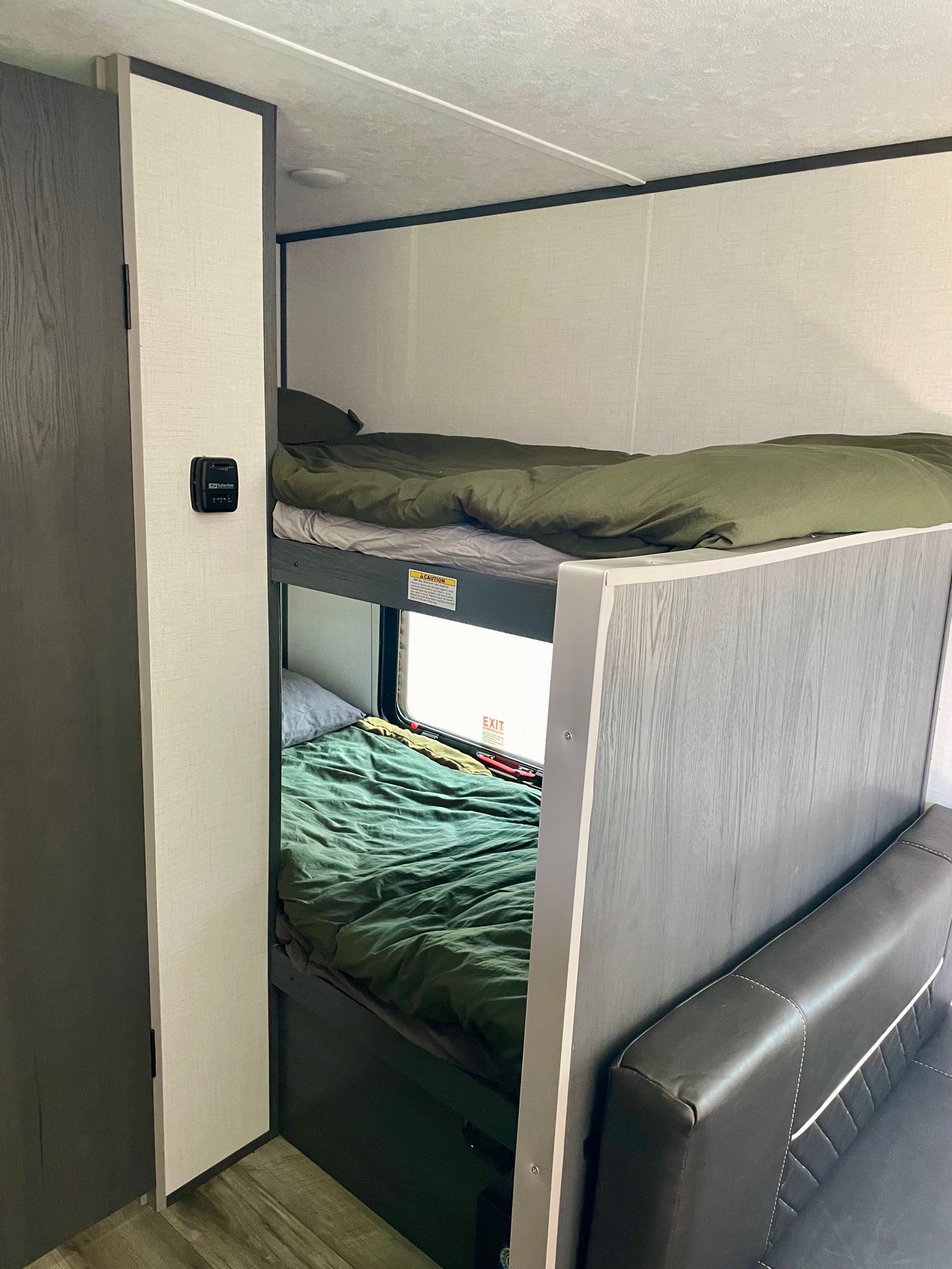 RV rental interior with comfortable bunk beds featuring green bedding, a window, and a control panel. Ideal for families.. Dutchmen Aspen Trail 2024