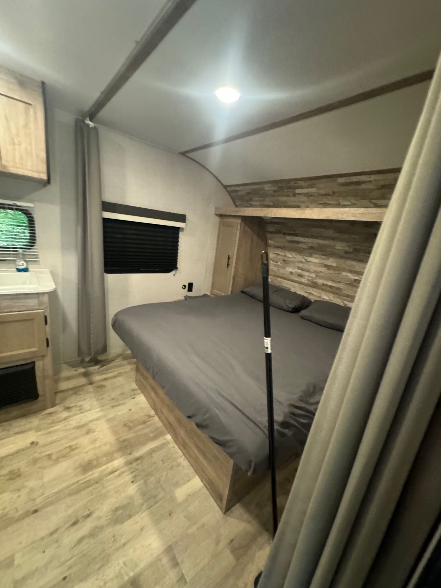 Modern RV rental bedroom with a comfortable queen bed, vanity sink, and wood accents, perfect for your road trip.. Gulf Stream Kingsport 2023
