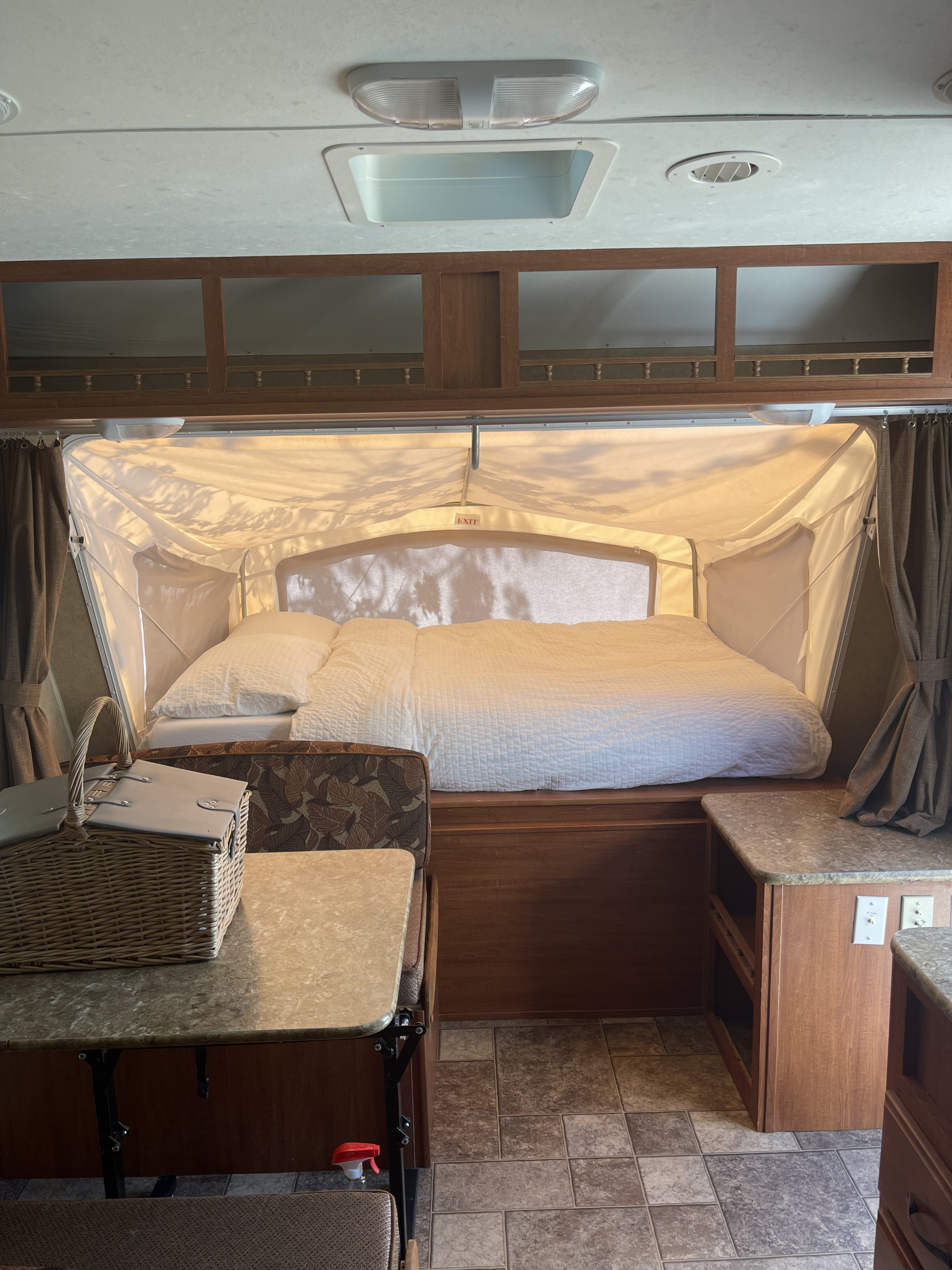 Cozy rv rental interior showing a comfortable pop-out bed, dinette area, and overhead storage.. Forest River Surveyor Sport 2012