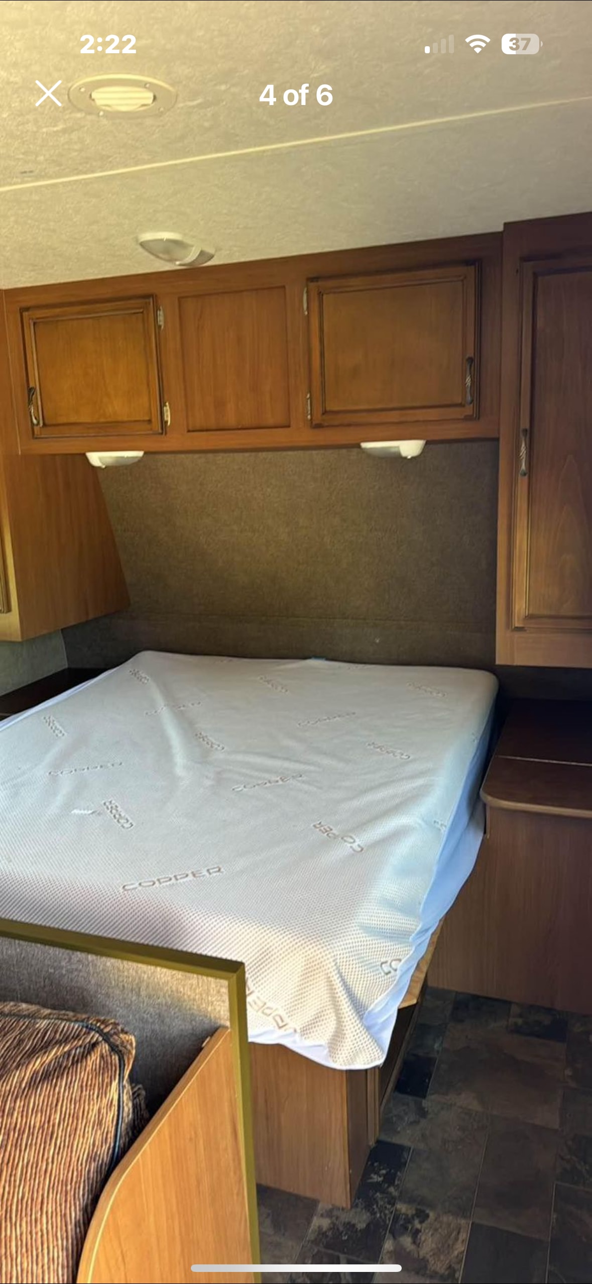 RV rental bedroom interior: large bed with "COPPER" cover, overhead wood cabinets, and built-in reading lights.. Starcraft Autumn Ridge 2013