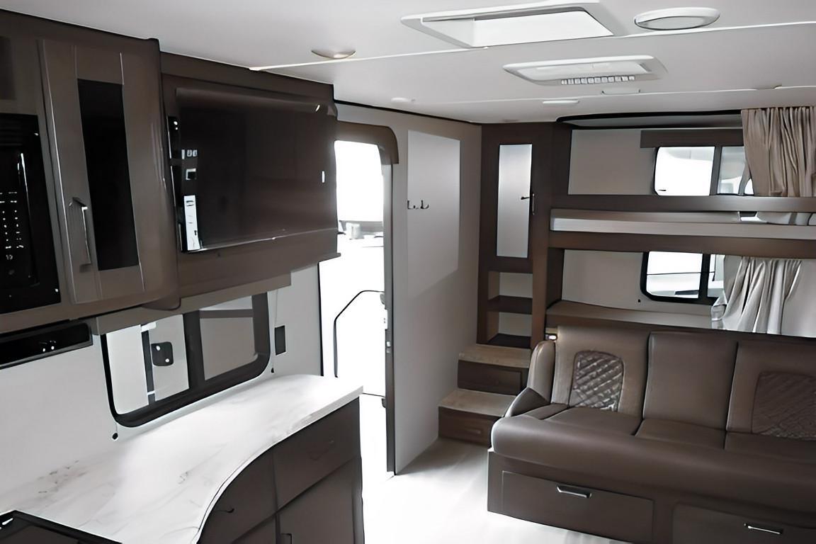 See inside this RV rental! Features a modern kitchenette, comfortable sofa, and bunk beds, optimizing space for travel.. Grand Design Transcend Xplor 2023
