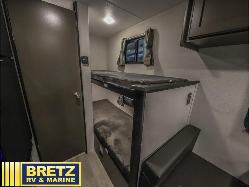 Inside this RV rental: a cozy bunk bed area and compact interior with a small bench seat and door.. K-Z RV Sportsmen Classic 2024