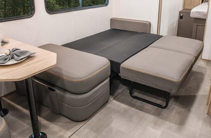 Versatile RV rental interior: A light gray sofa/dinette seamlessly converts into a comfortable bed, optimizing compact living.. Cruiser RV Avenir 2024
