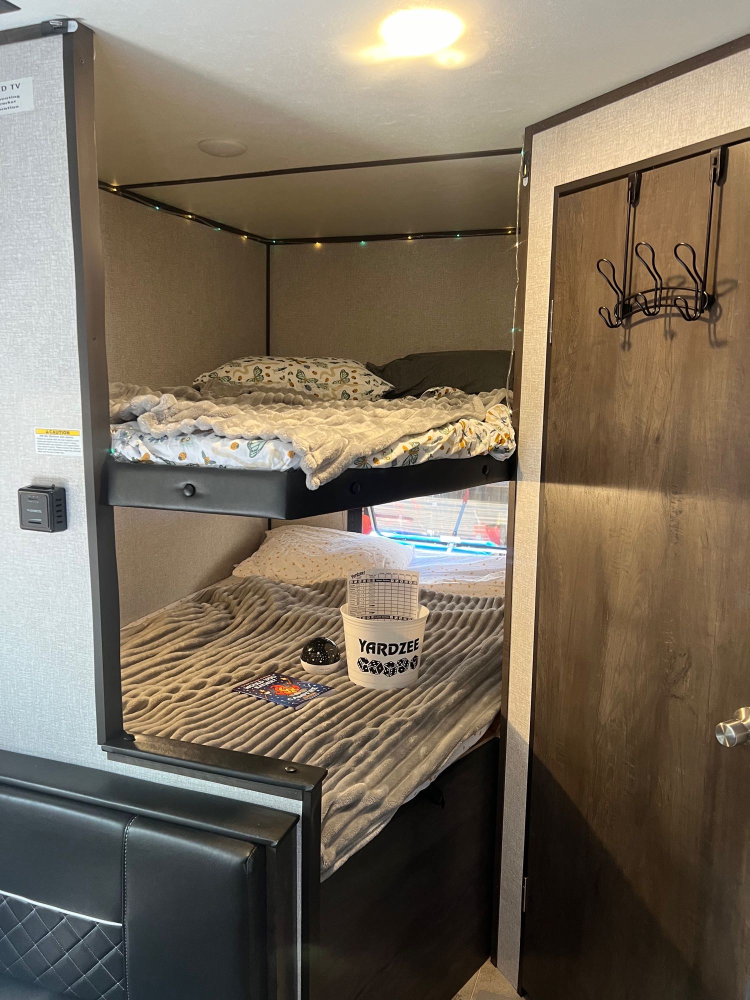 Inside a cozy RV rental: two bunk beds with festive string lights and soft bedding.. Dutchmen Coleman Lantern LT 2021