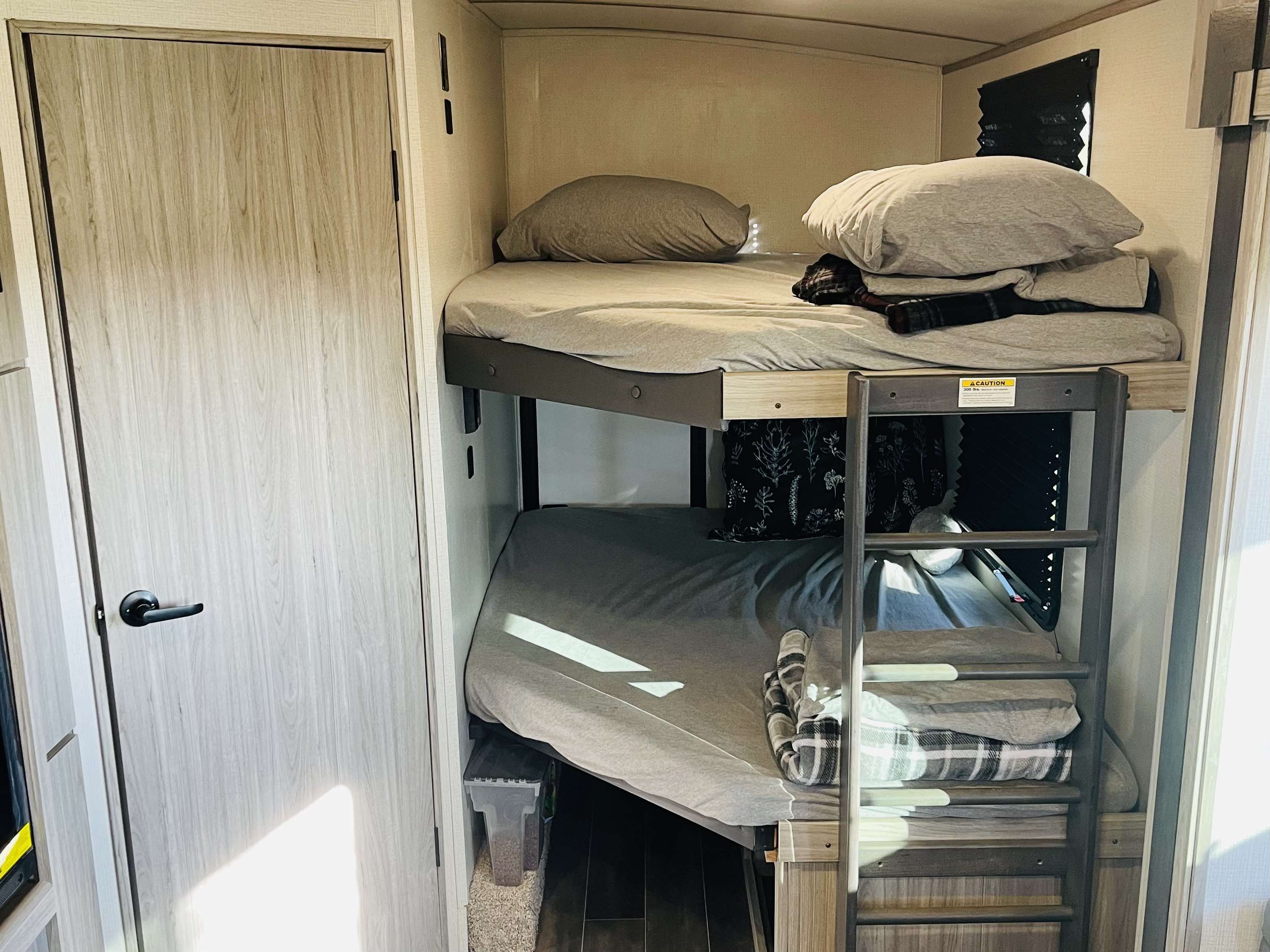 Inside an RV rental: comfy bunk beds for a cozy sleeping area. Ideal for family road trips & travel adventures.. Keystone RV Passport GT Ultra Lite 2023