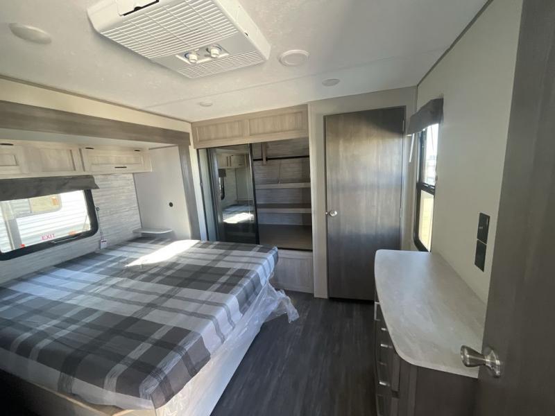 RV rental bedroom features a plaid bed, ceiling AC, mirrored closet, and dresser for a comfortable stay.. Forest River Aurora 2024