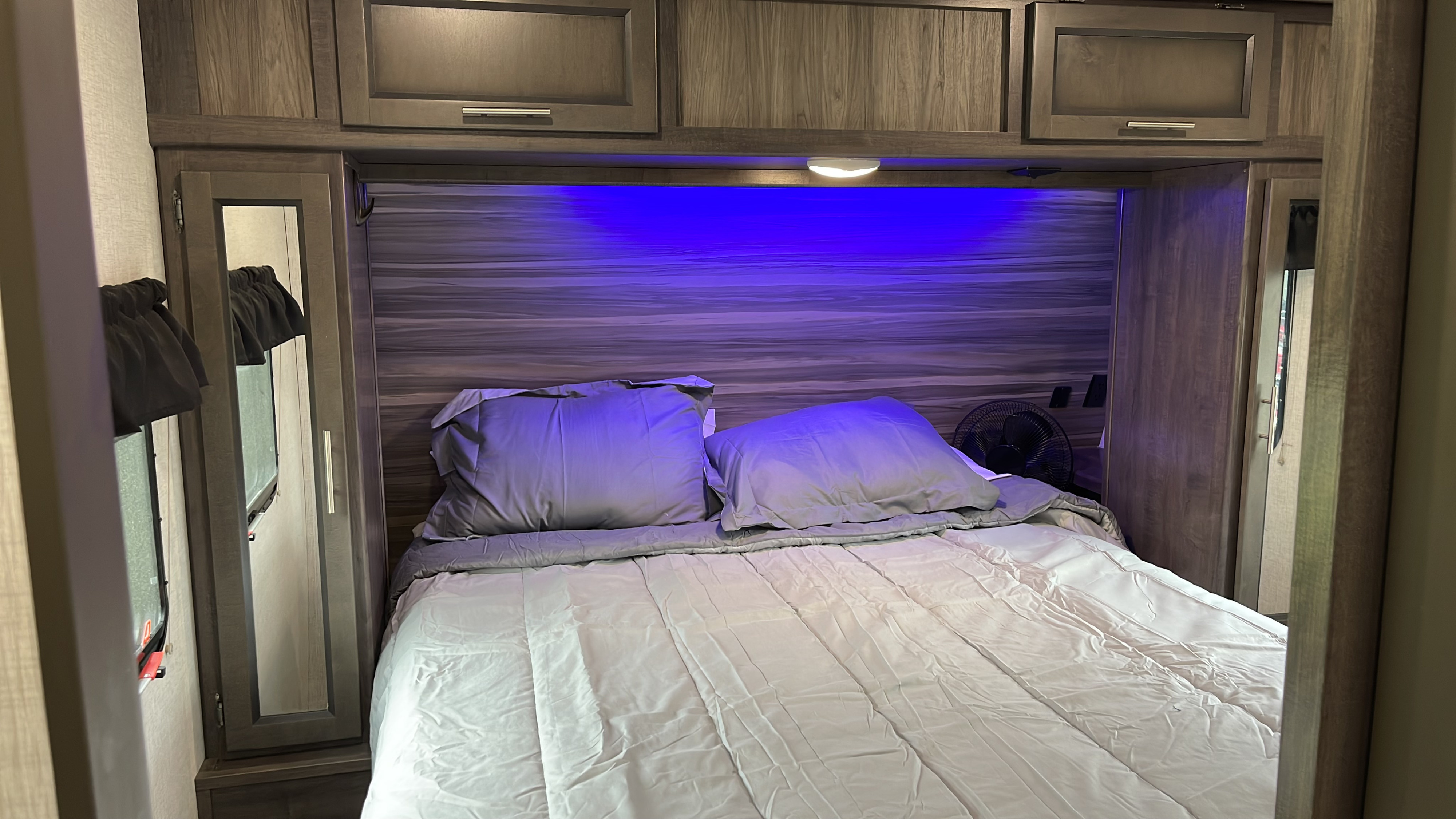 Cozy RV rental bedroom featuring a comfortable bed, overhead storage, and atmospheric blue lighting for a relaxed stay.. Crossroads SS288BH 2020