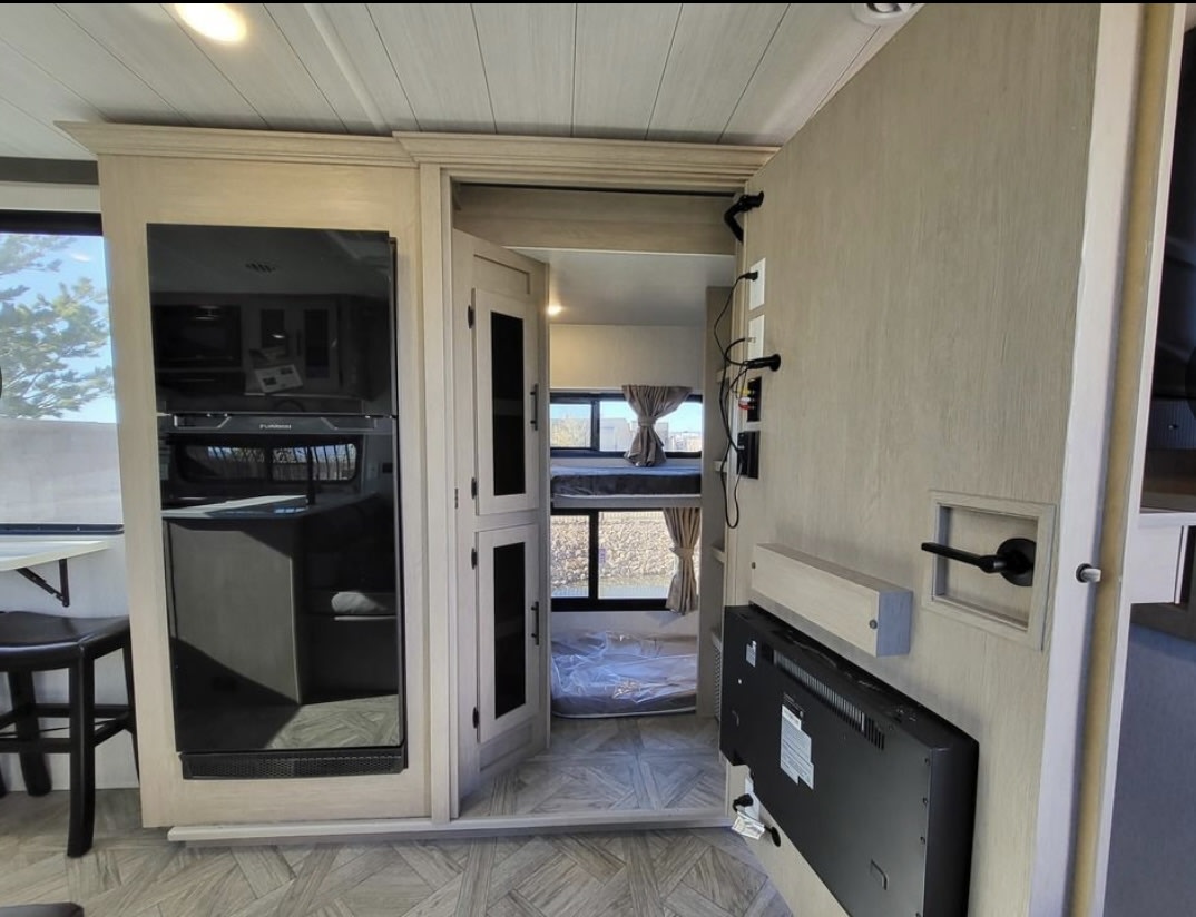 Inside a modern rv rental: kitchen appliances, entertainment wall, and bunk beds. Perfect for family adventures.. Forest River Wildwood X-Lite 2024
