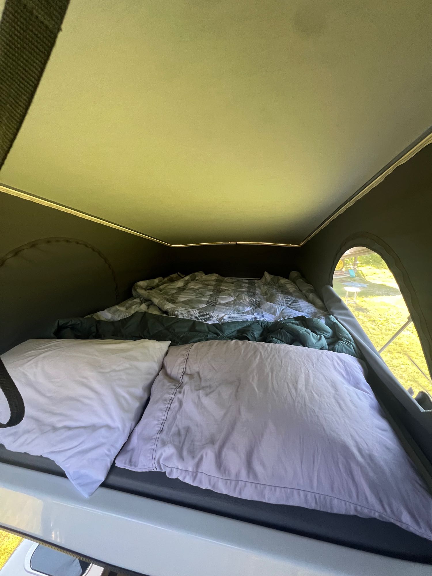 Inside an RV rental pop-top camper: a cozy bed with pillows and blankets, offering a comfortable sleeping space for travel.. Winnebago Solis 59P 2022