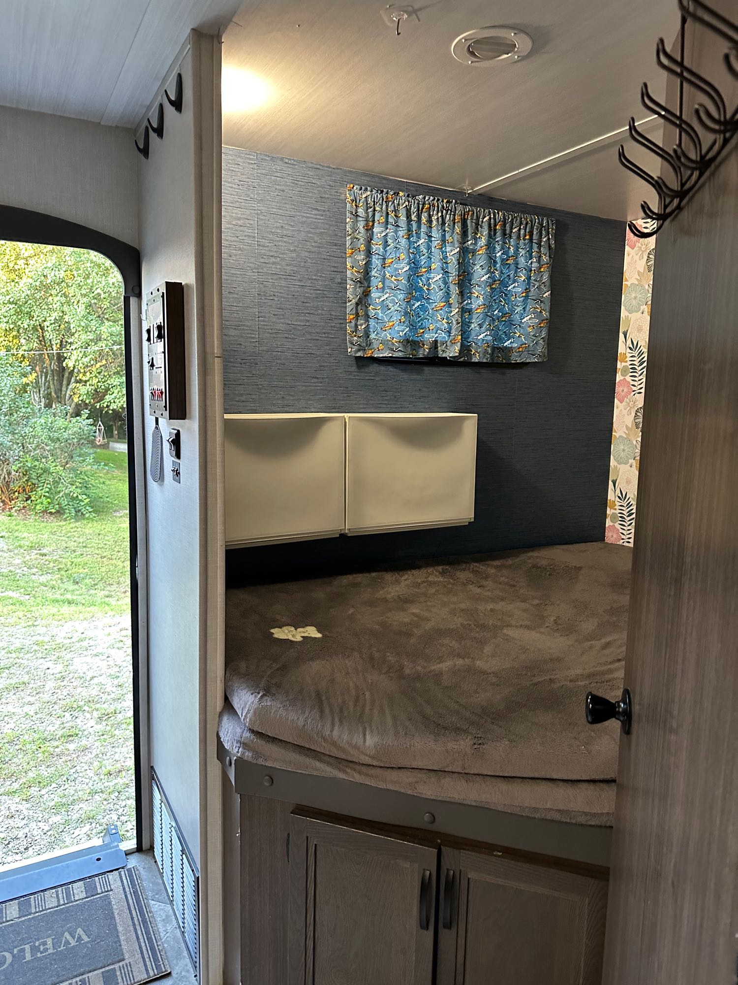 This inviting RV rental offers a cozy bed area with blue textured walls, window, and direct outdoor view.. Winnebago Voyage 2021