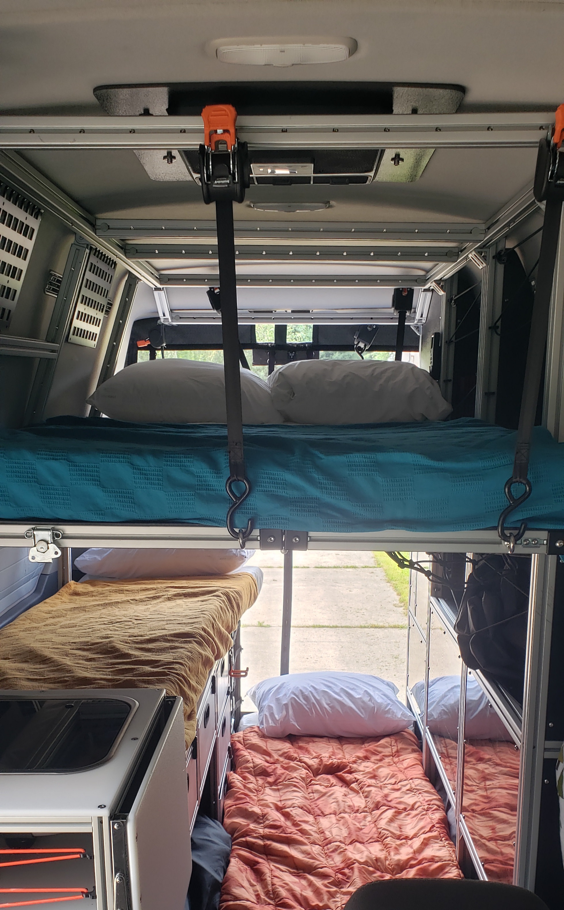 An RV rental camper's interior showcases a suspended top bunk and two lower beds, ideal for multi-person sleeping.. Ford Transit Custom 2019