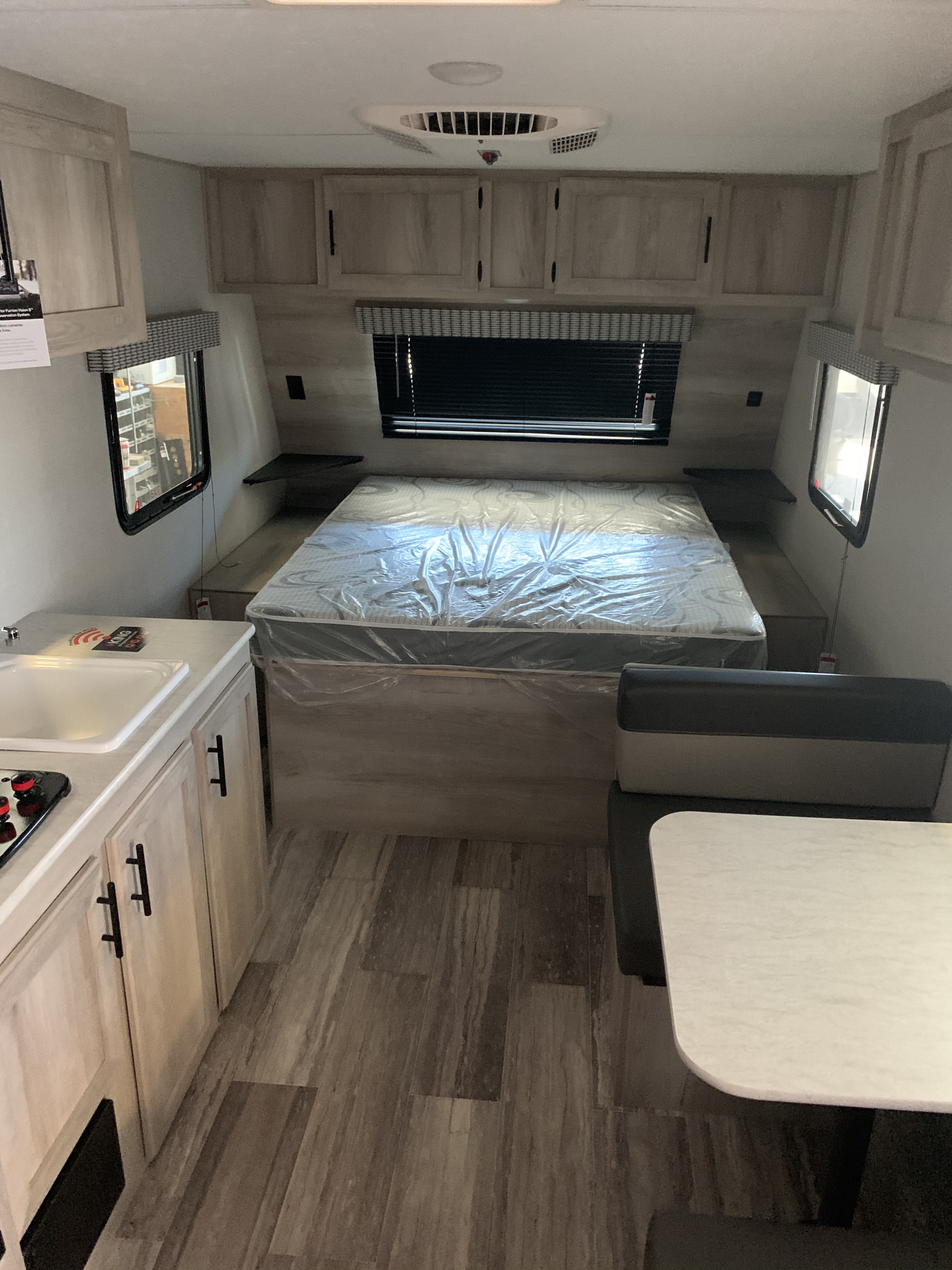 New RV rental interior featuring a bedroom with covered mattress, compact kitchen, and dinette.. KZ Sportsmen classic 160QB 2021