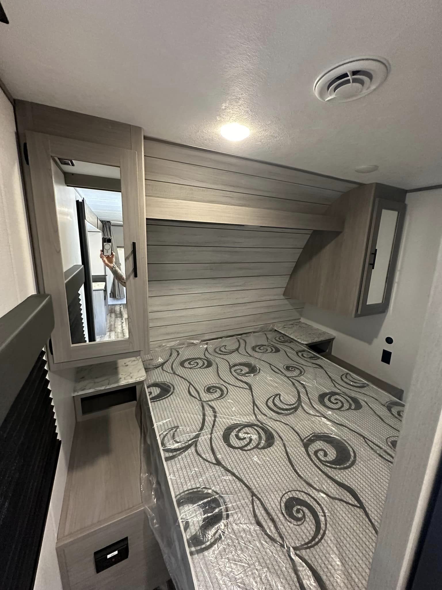 RV rental bedroom featuring a bed, overhead storage, and mirrored cabinets. Compact interior view.. Coleman Lantern LT 263 BH 2024