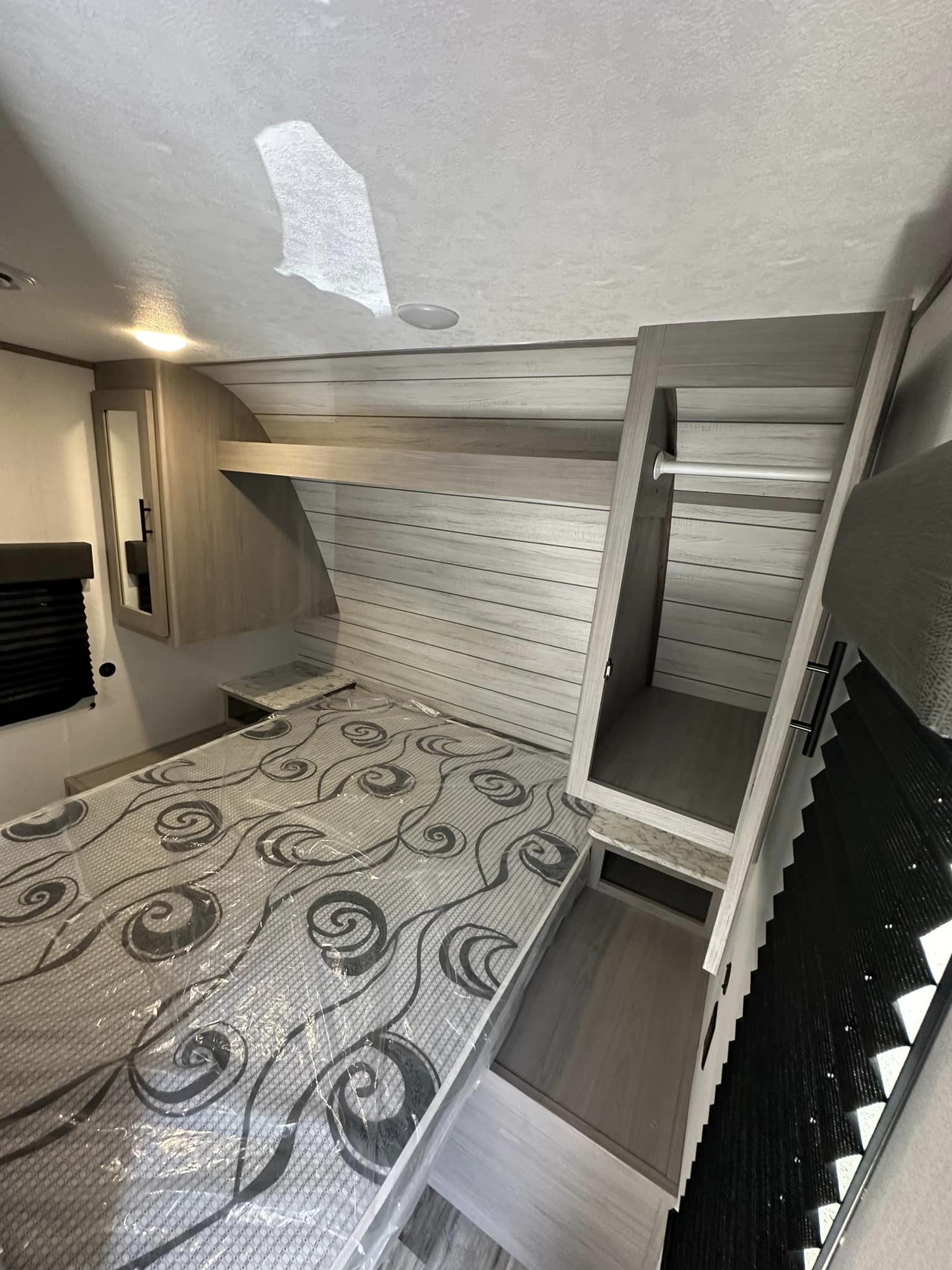 Inside an RV rental bedroom: light wood furnishings, a bed with new plastic-wrapped mattress, and ample storage.. Coleman Lantern LT 263 BH 2024