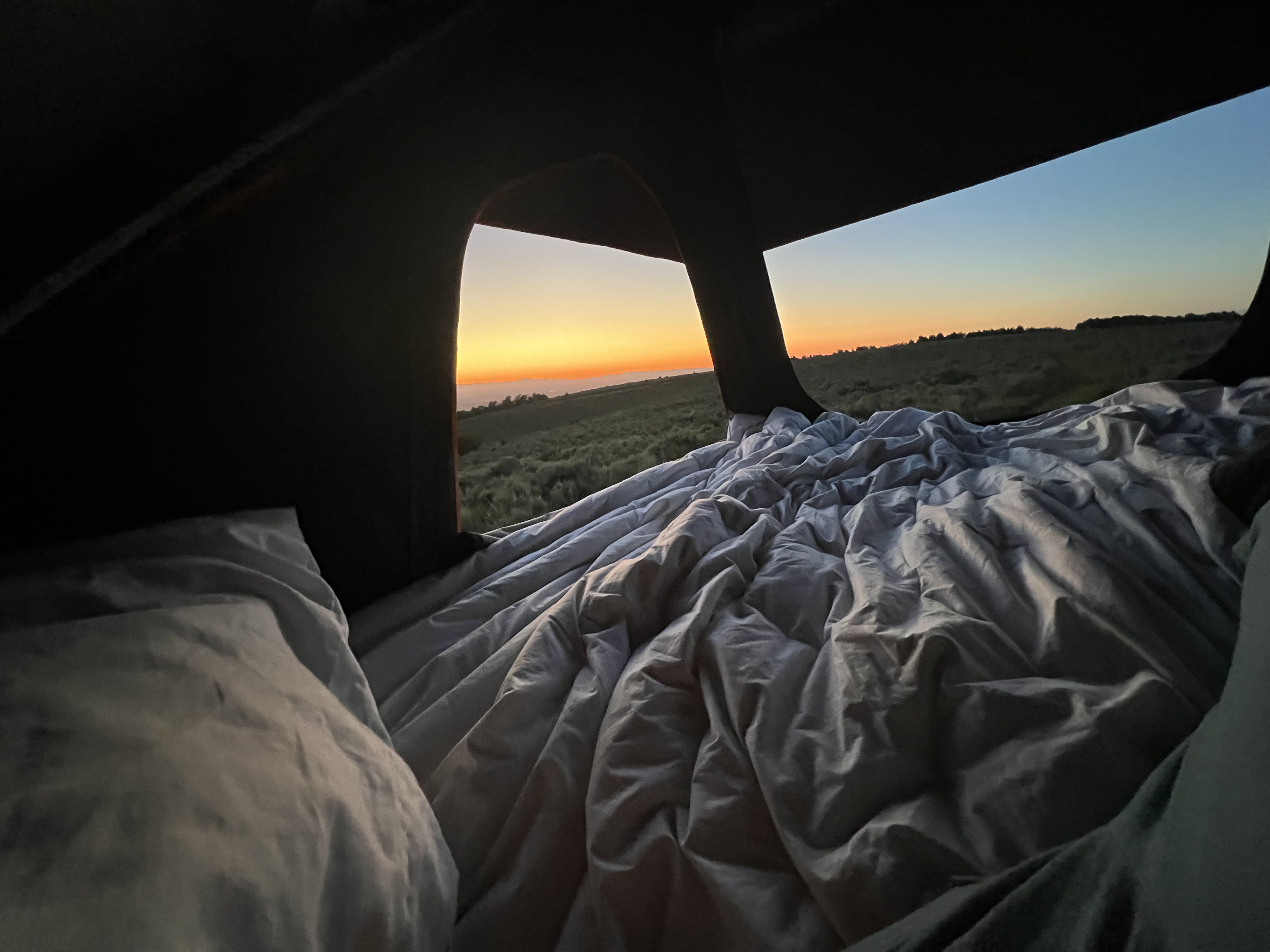 Waking to a serene sunrise from a cozy, unmade bed inside an rv rental. Rolling green hills in view.. Honda Pilot 2012