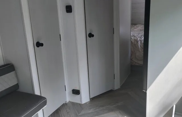 Compact RV rental interior: hallway with white doors, a bench, and a peek into a modern bedroom.. Forest River Salem 2021