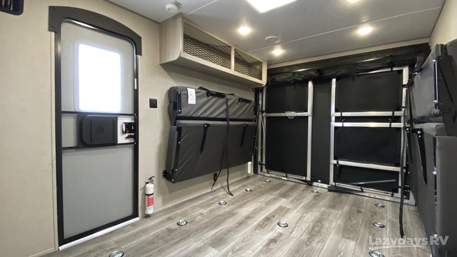 Interior of an RV rental toy hauler, showing versatile garage space with fold-down beds, tie-downs, and entry door.. Coachmen Catalina 2023