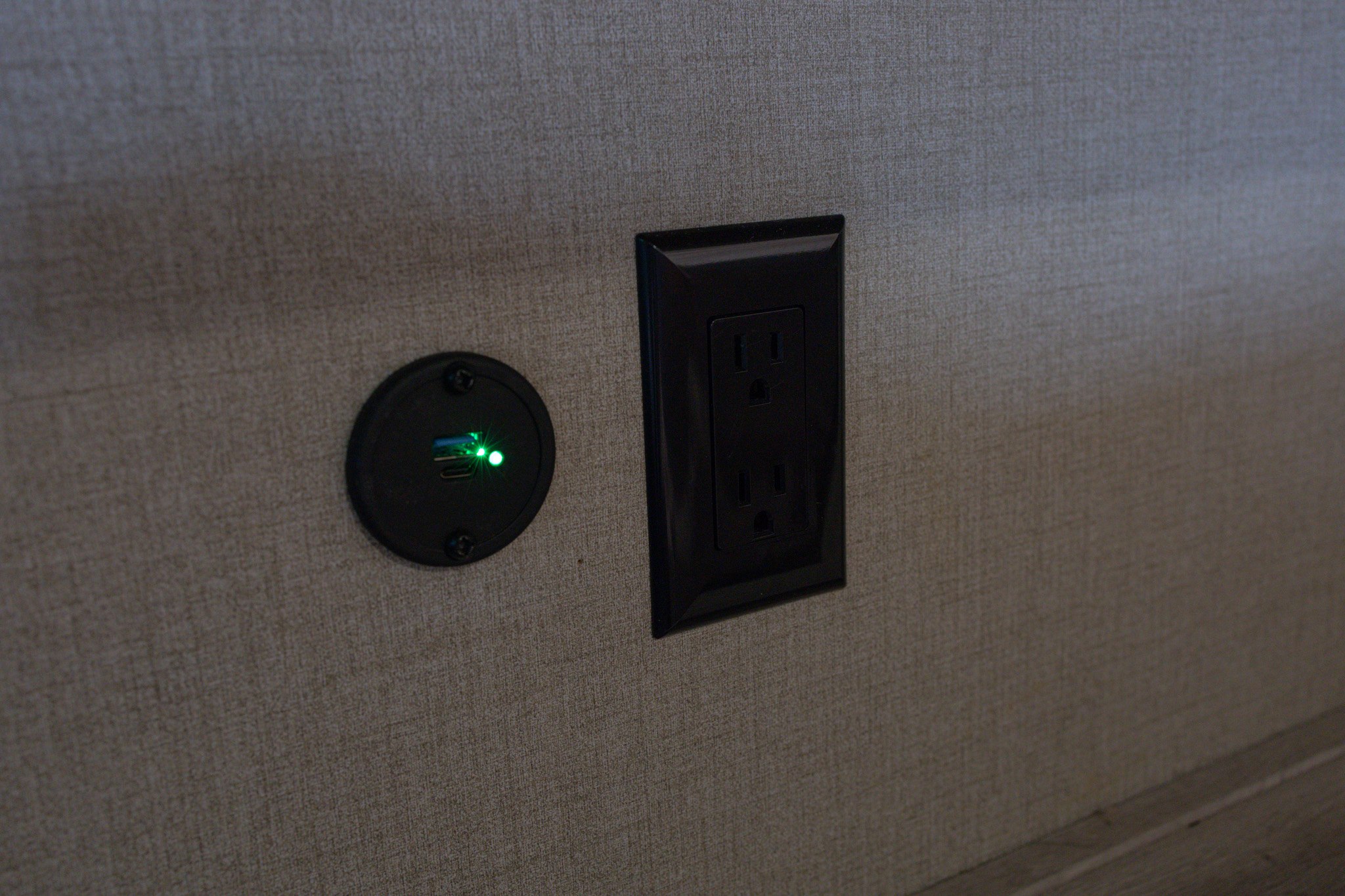 RV rental convenience: Illuminated USB charging ports and a standard electrical outlet on a textured wall.. Coachmen Catalina 2023