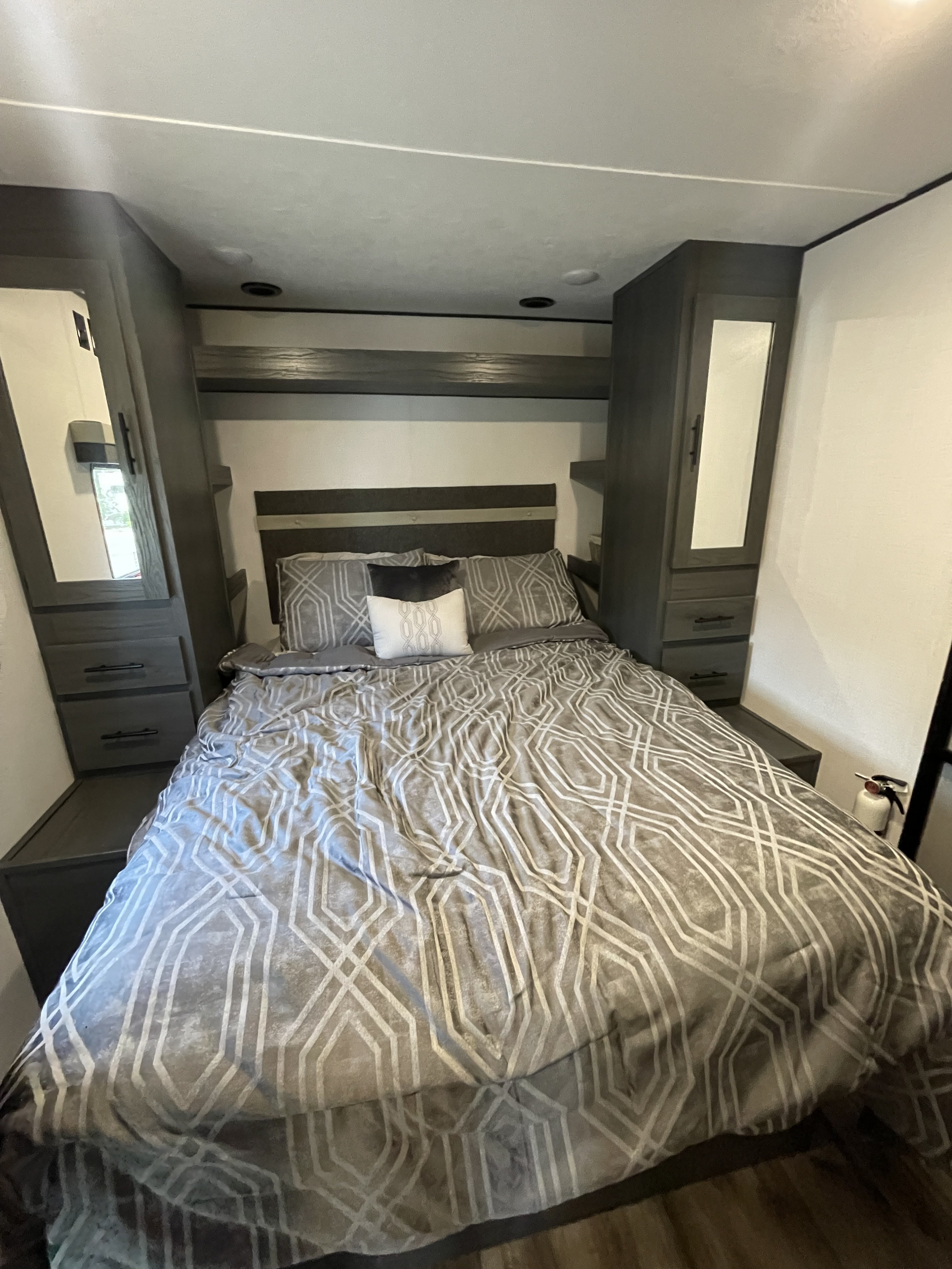 Inside this **RV rental**: a modern, compact **bedroom** with grey geometric **bedding**, mirrored **wardrobes**, and storage.. Dutchmen Colorado 2024