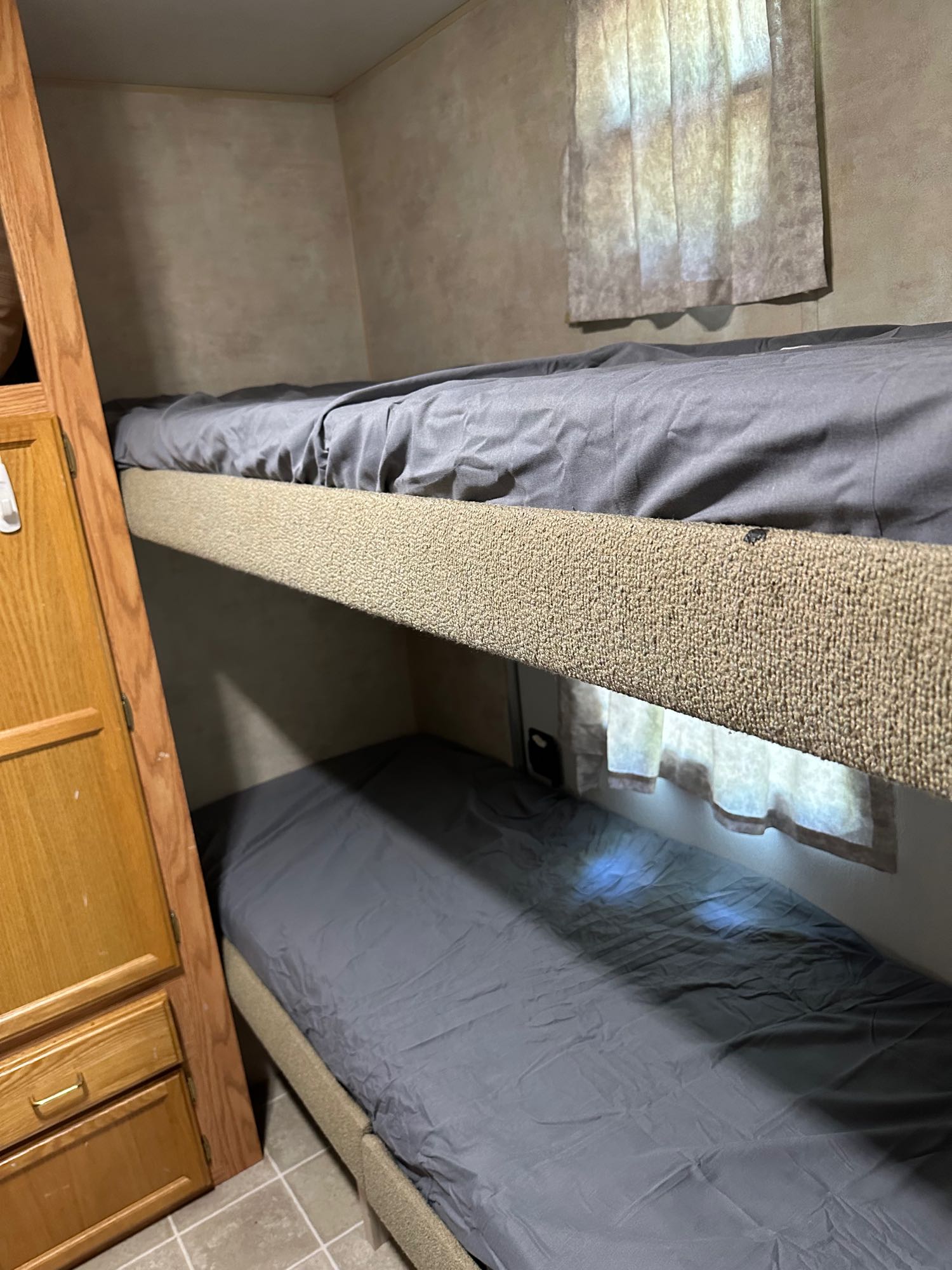Cozy RV rental features bunk beds with gray sheets, providing compact sleeping for your adventures.. Jayco Jay Flight 2003