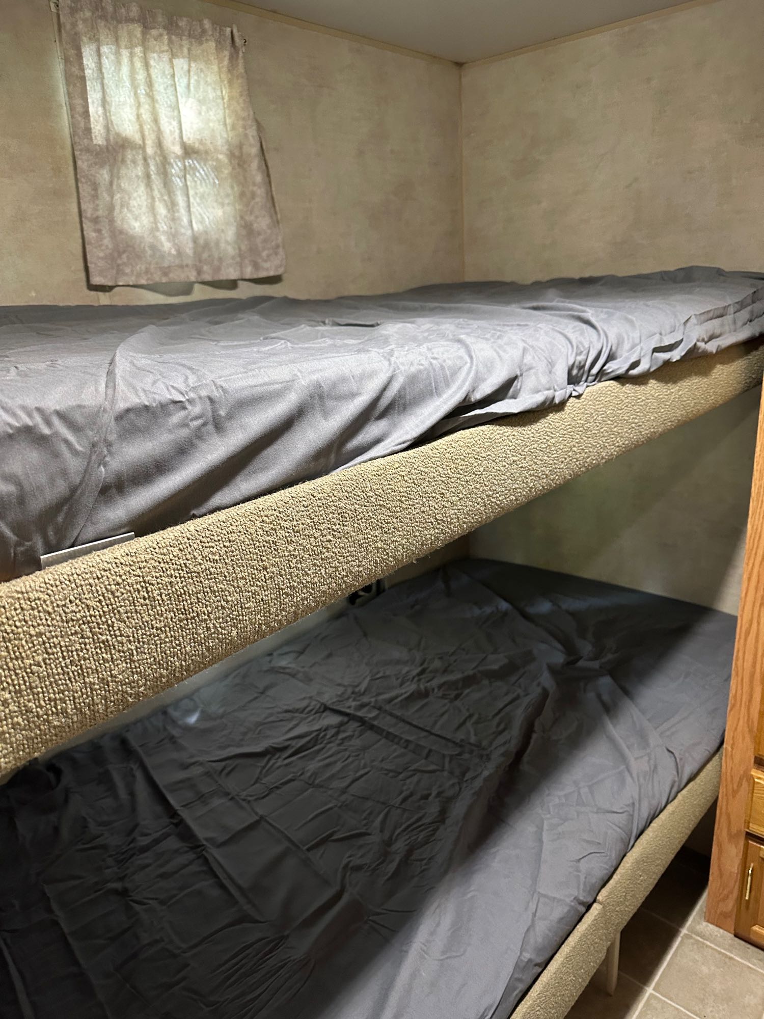 Cozy RV rental bunk beds with gray sheets and a window, ideal for extra sleeping space on your trip.. Jayco Jay Flight 2003