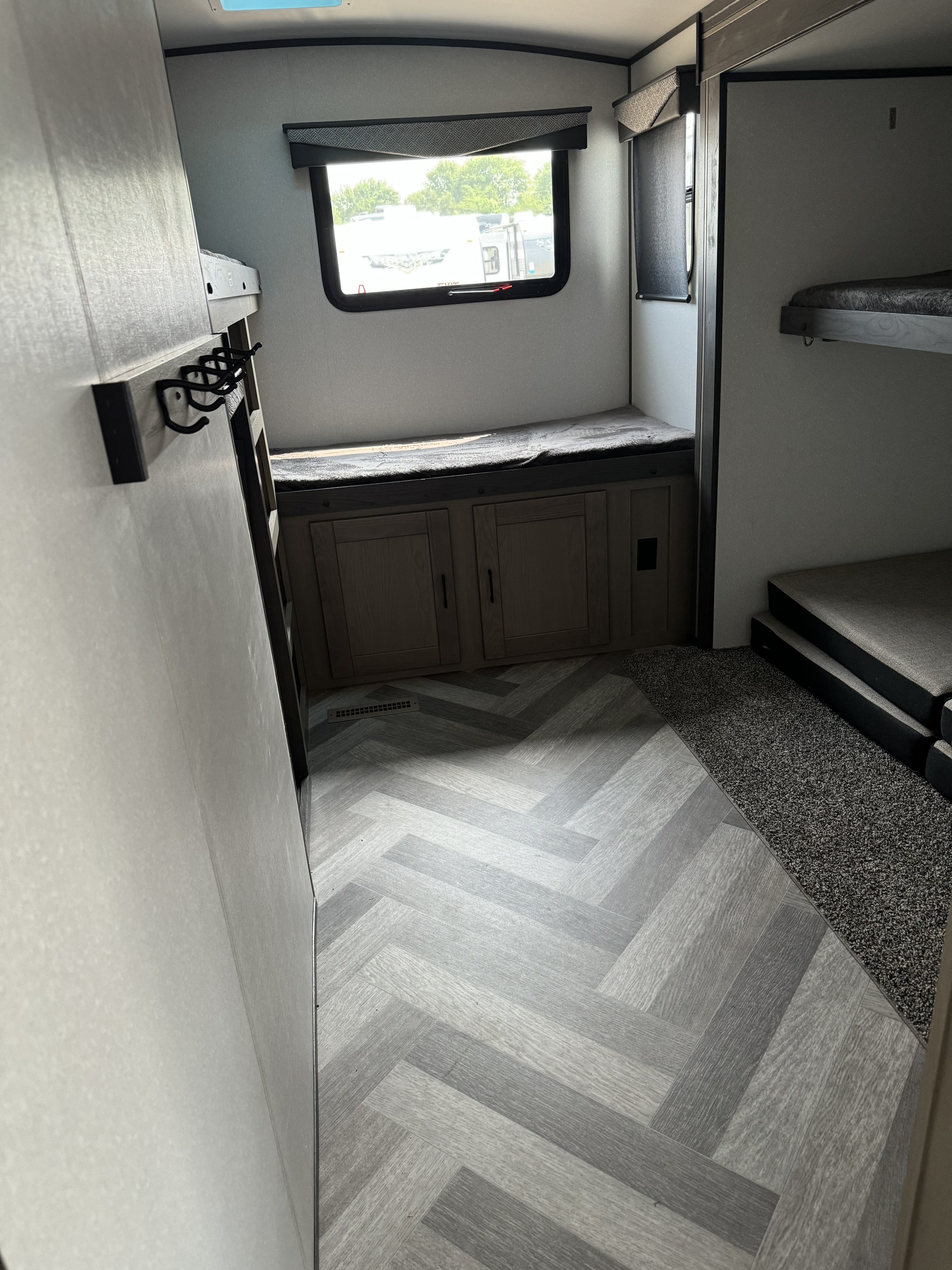 RV rental interior: herringbone floor, cozy bunk beds on right, and a bench with storage by the window.. Heartland Other 2021